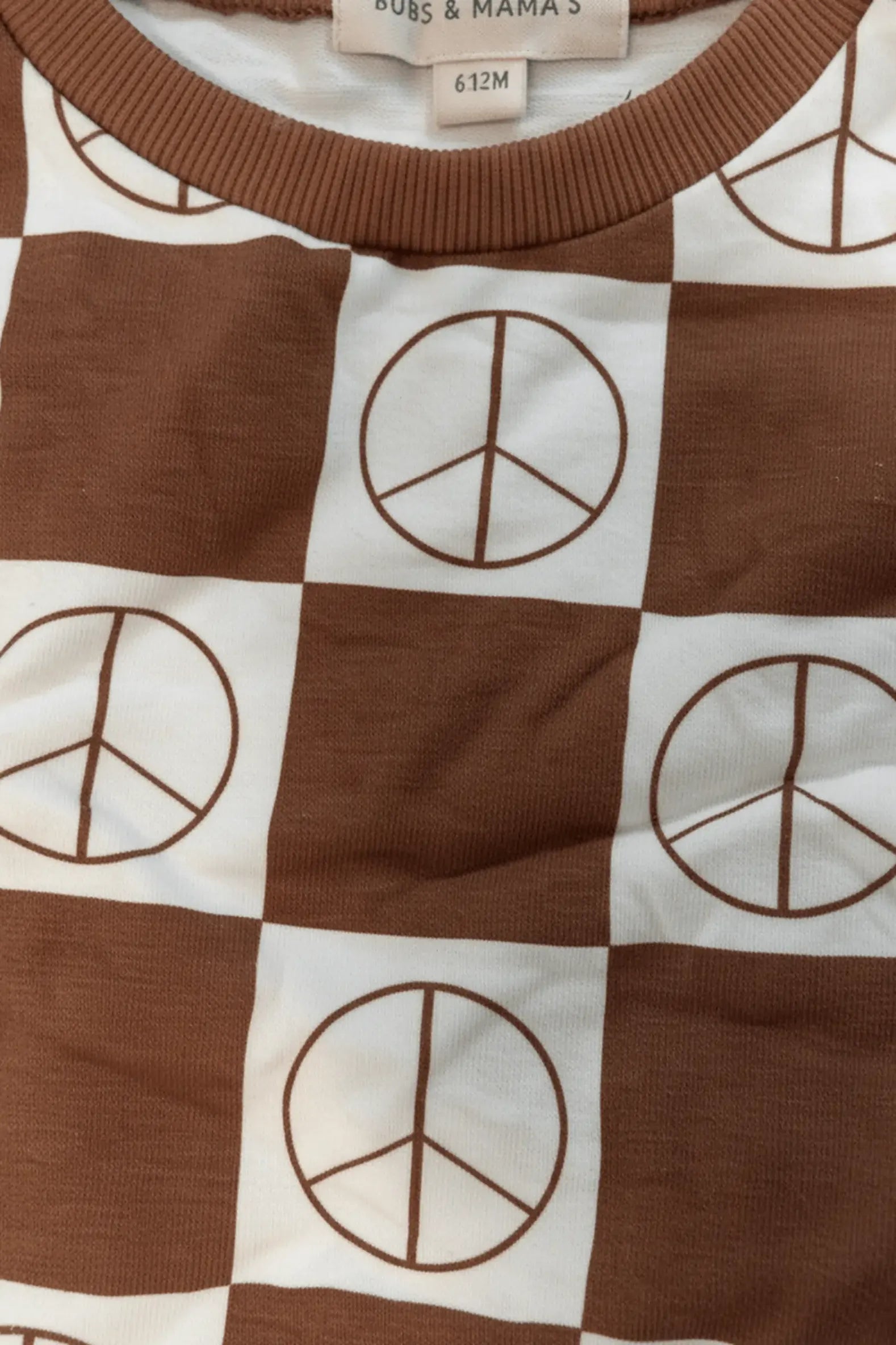 Brown and white checkered fabric with peace symbol pattern, brand label visible.