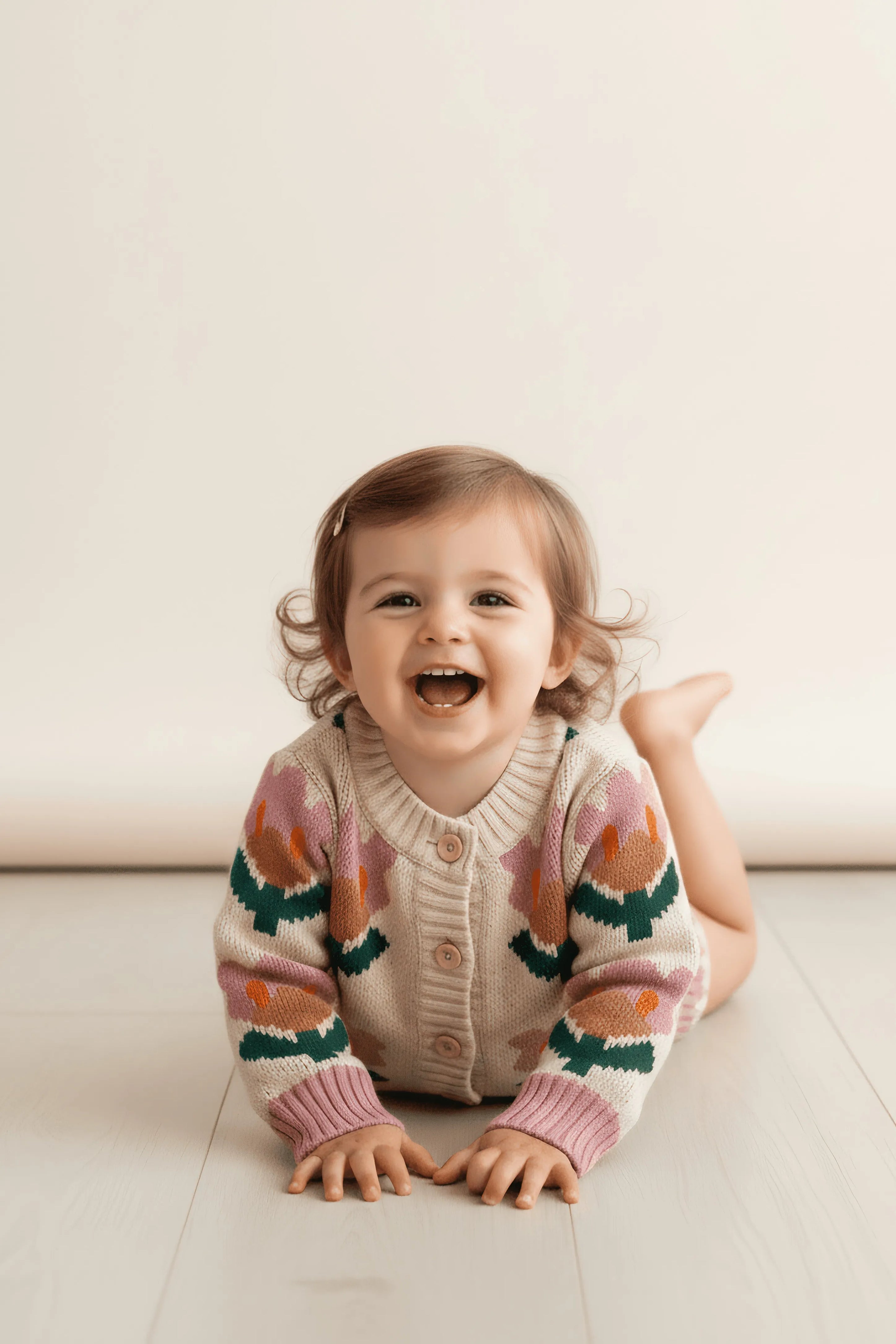 Child wearing a patterned Bubba's and Mama's cardigan sitting on a light-colored floor.