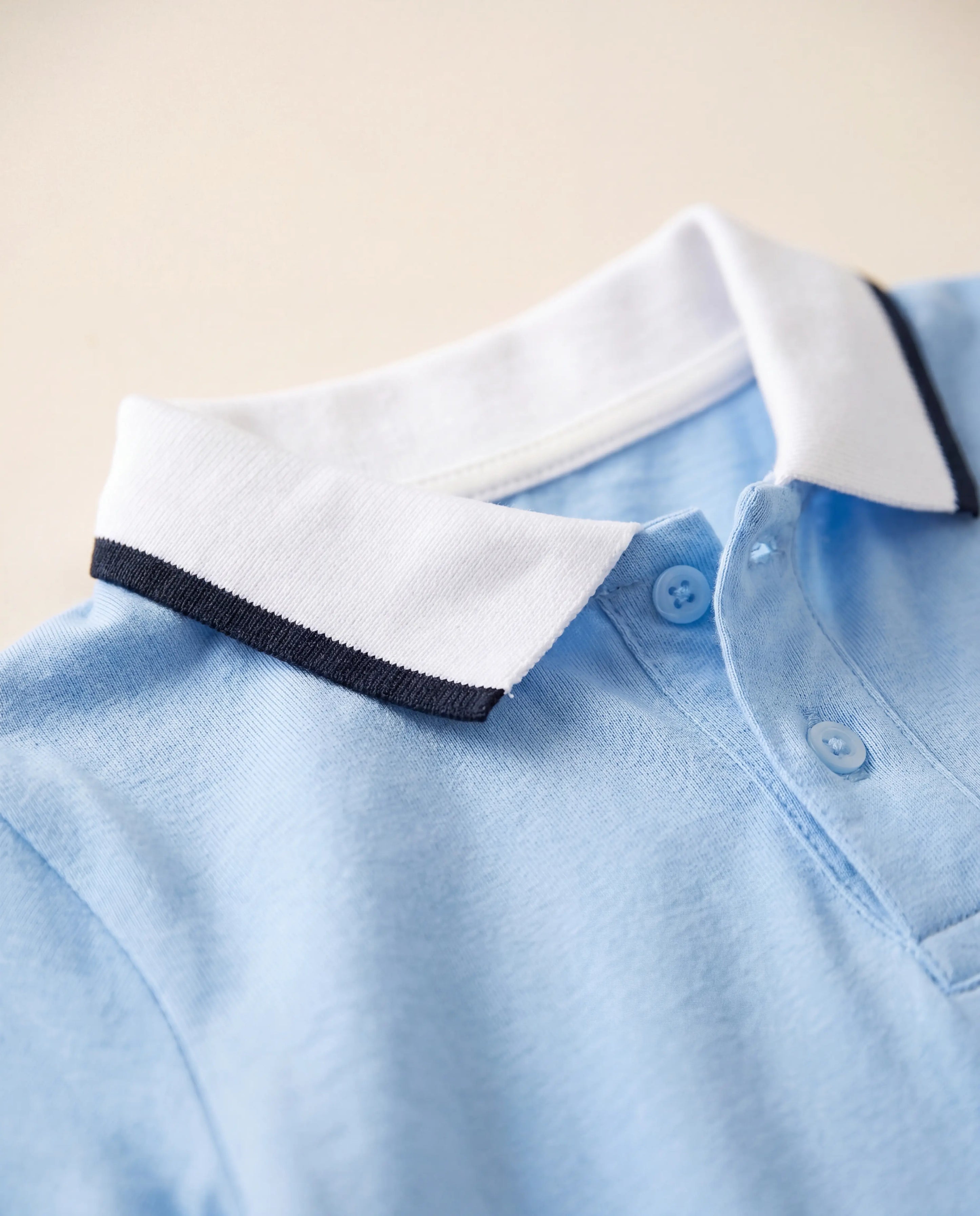 Close-up of white polo collar with contrast trim on blue baby romper