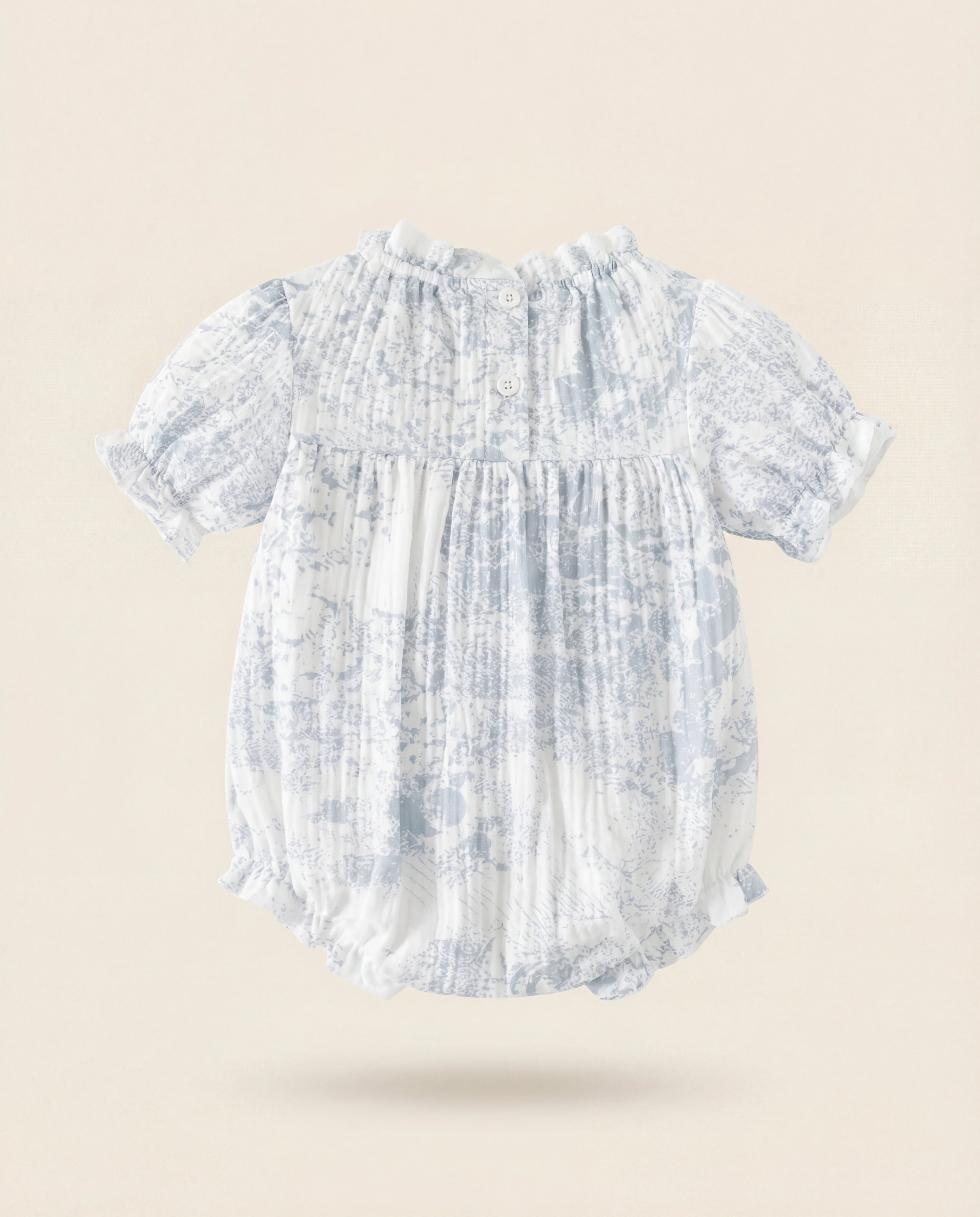 Baby romper with blue and white tie-dye pattern on a beige background