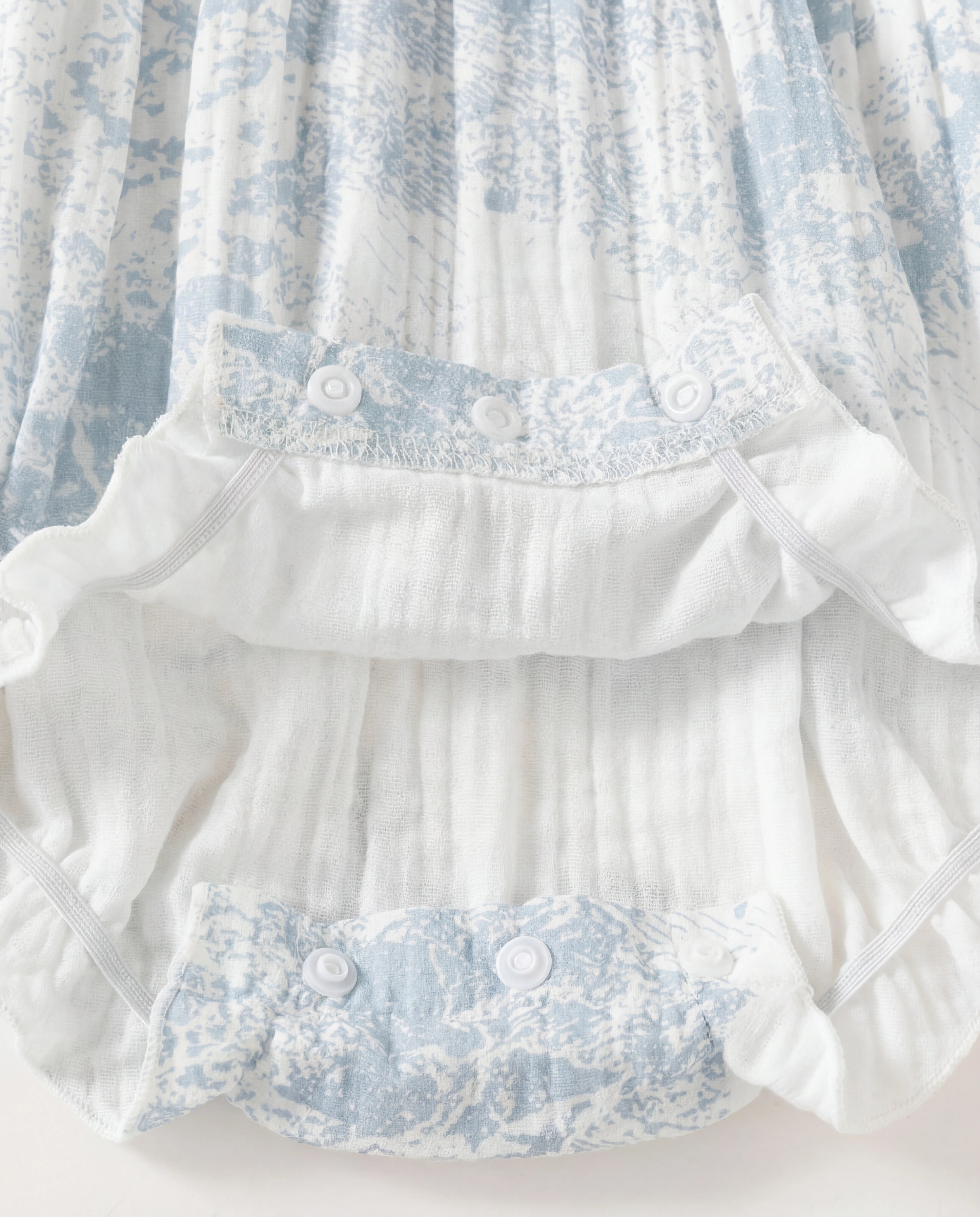 White fabric with blue floral lace trim on a white background