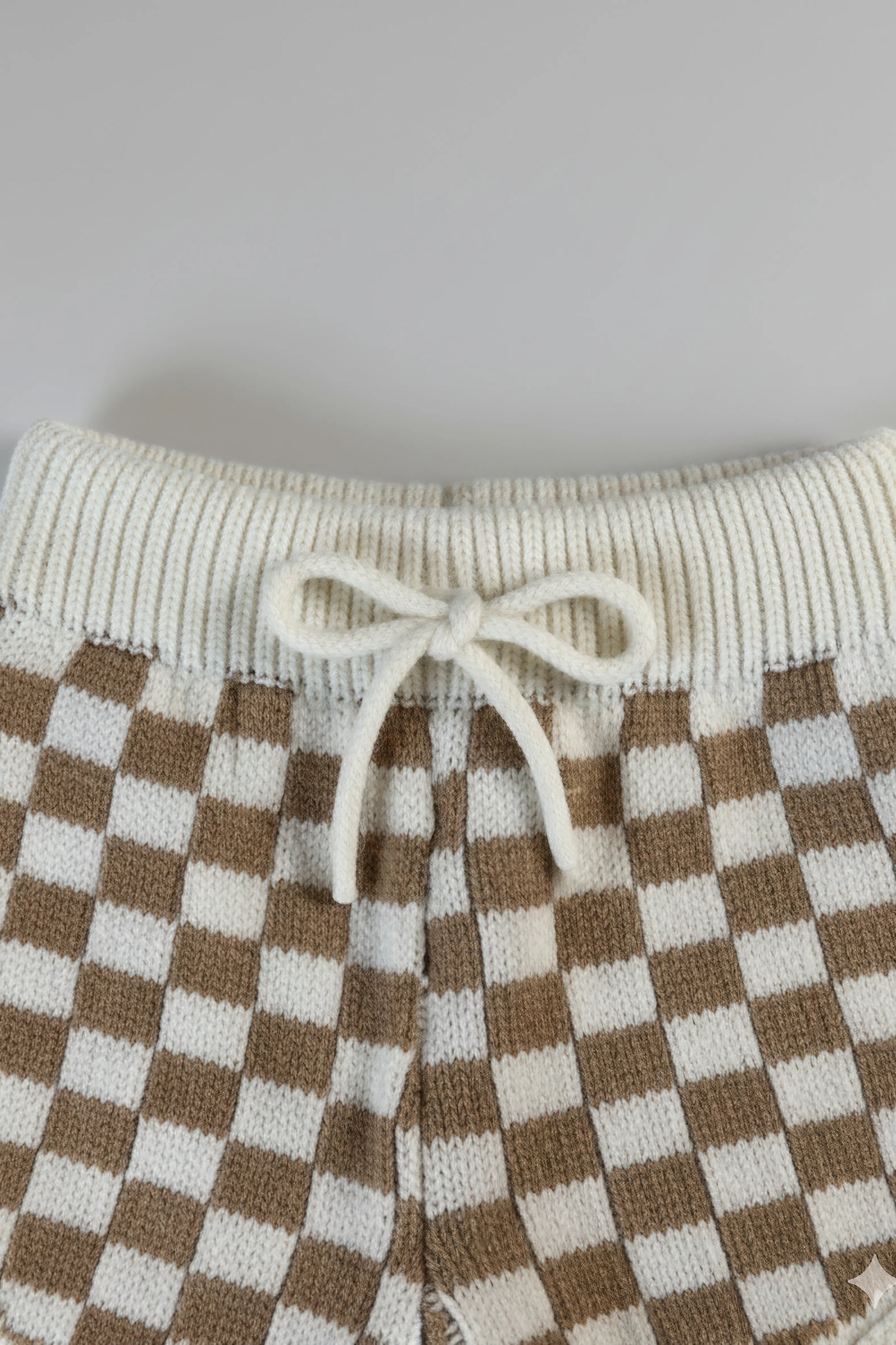 Checkered pants with a white drawstring on a light gray background
