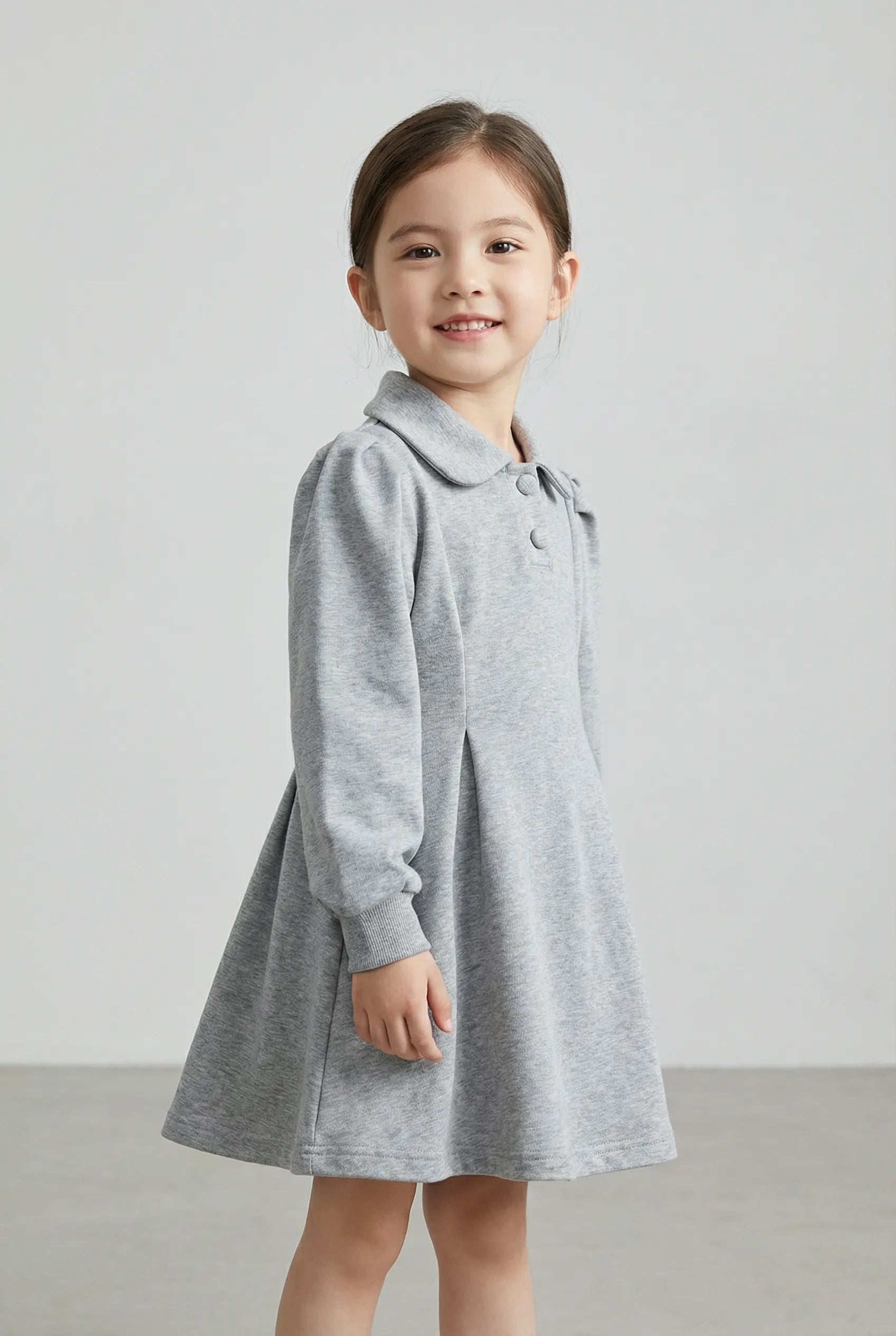 Young girl wearing a gray dress against a plain background