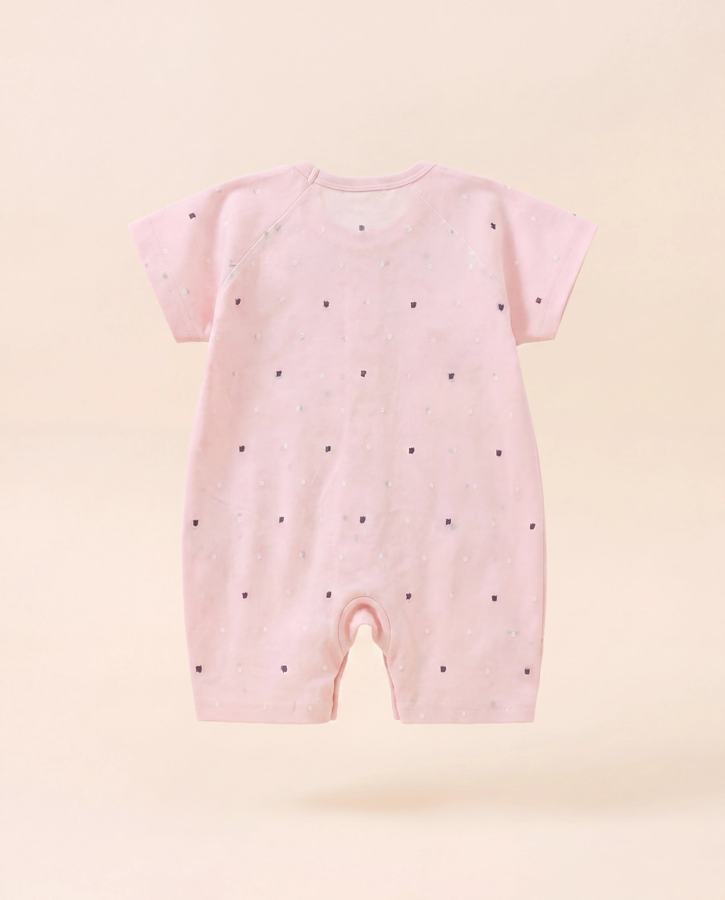 Pink baby romper with black polka dots on a light pink background