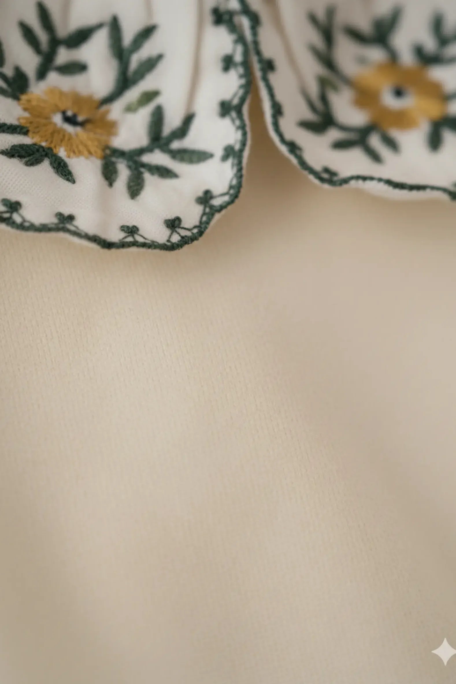 Close-up of a beige Bubba's and Mama's fabric with floral embroidery on a white background