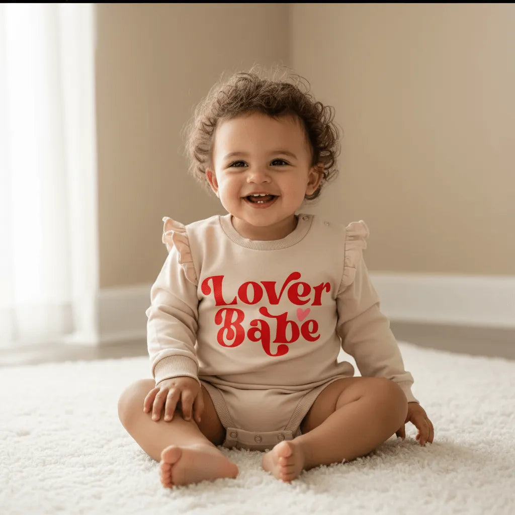 Child wearing a 'Lover Babe' onesie sitting on a carpeted floor.