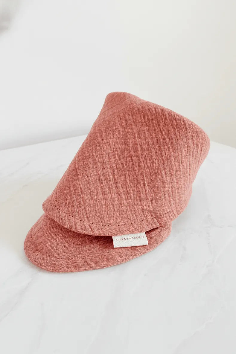 Our Pink textured baby bib on a white surface with our brand label.