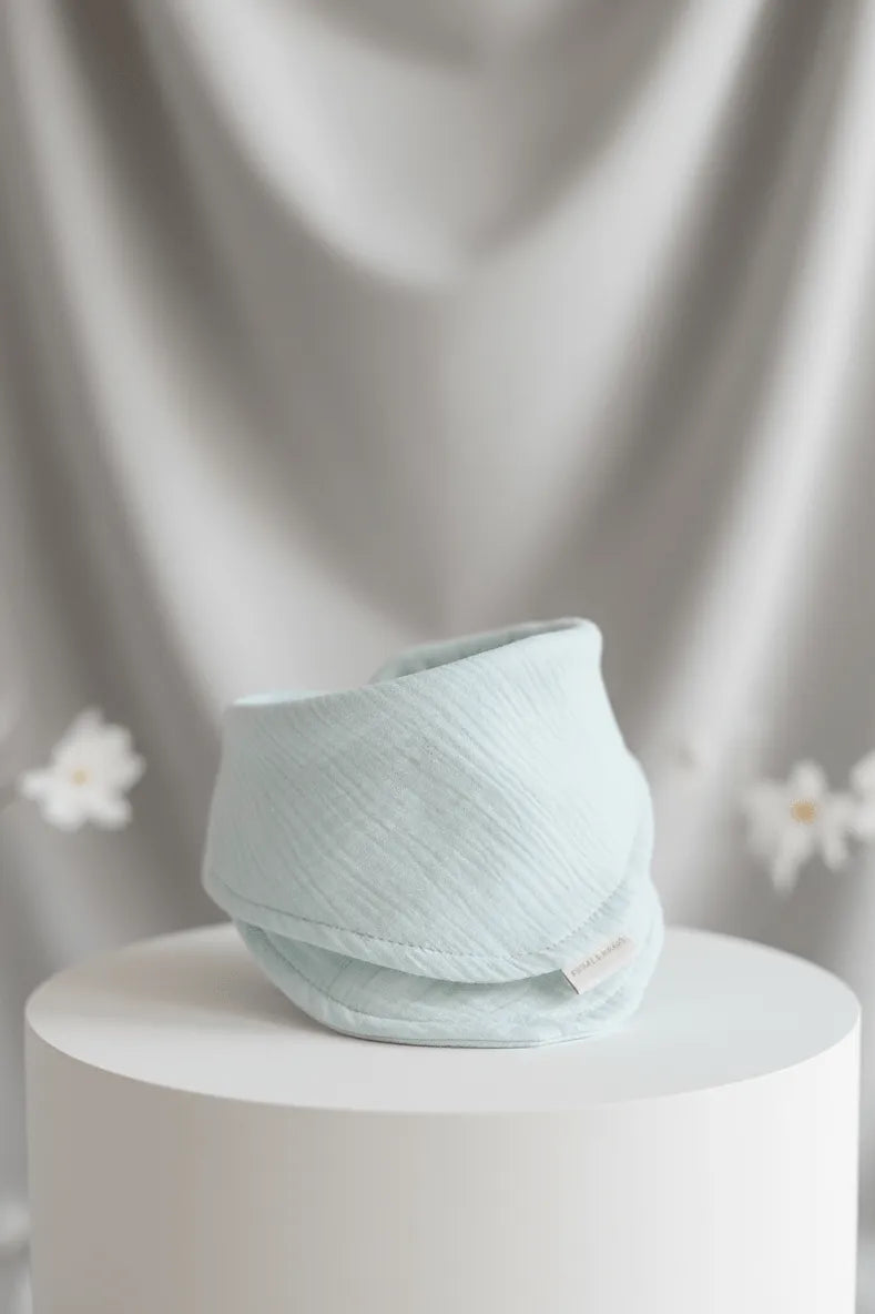 Light blue woven basket on a white pedestal with a soft gray curtain background