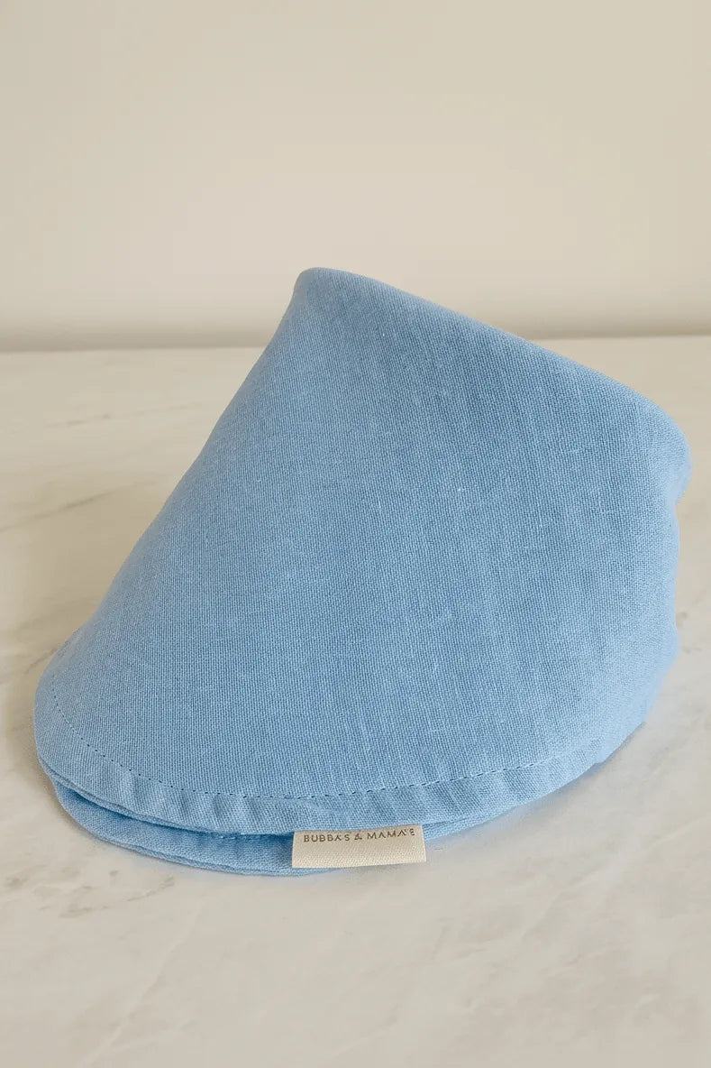 Blue baby bib on a light gray surface with a visible brand label.