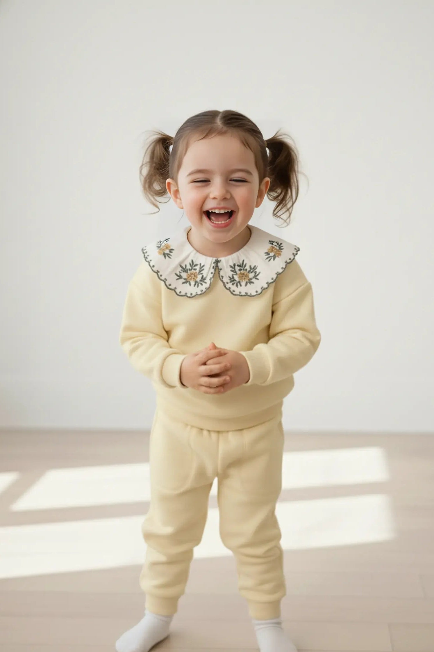 Child wearing a cream-colored Bubba's and Mama's outfit with a decorative collar on a light background