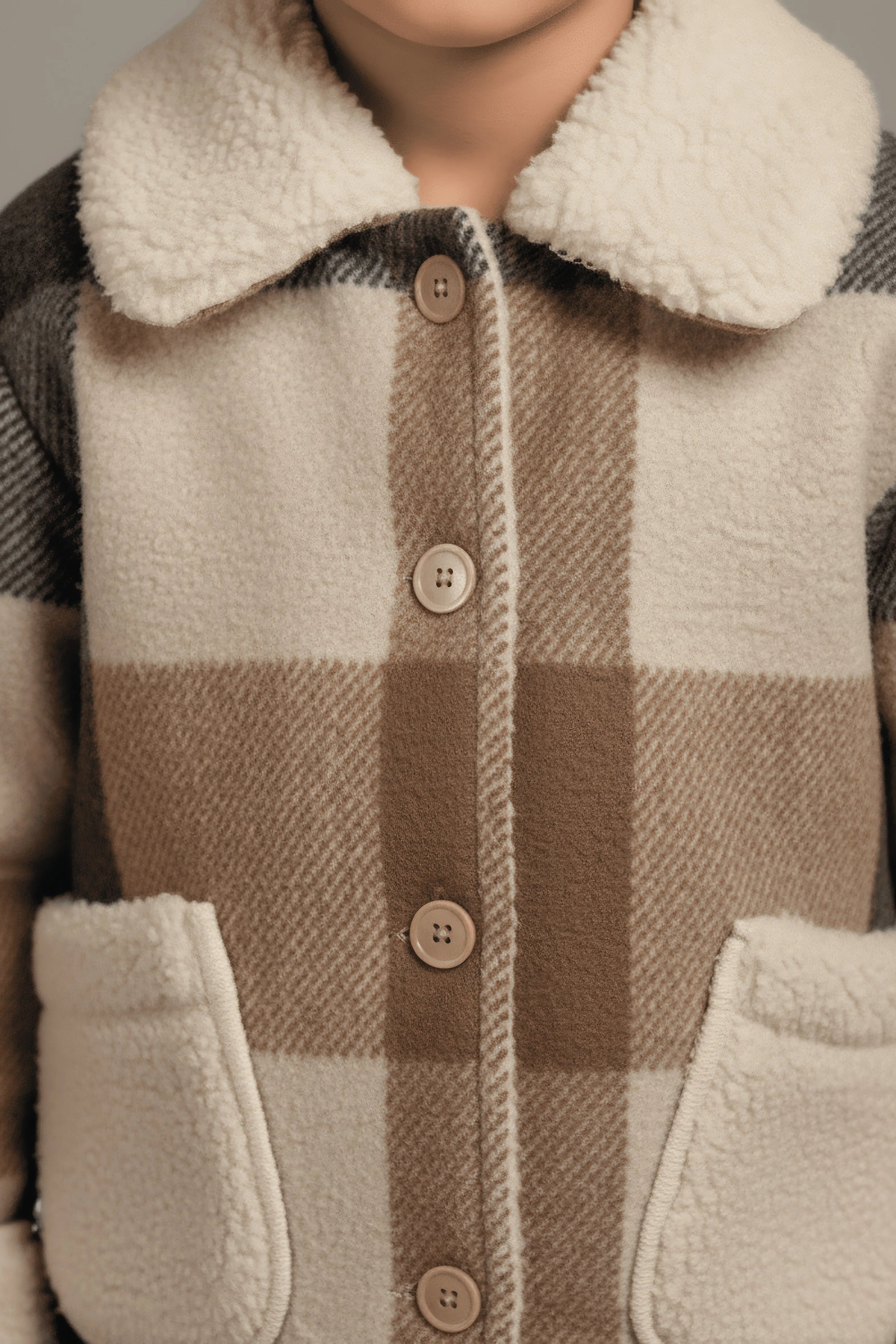 Close-up of a checkered Bubba's and Mama's coat with a textured collar and buttons.