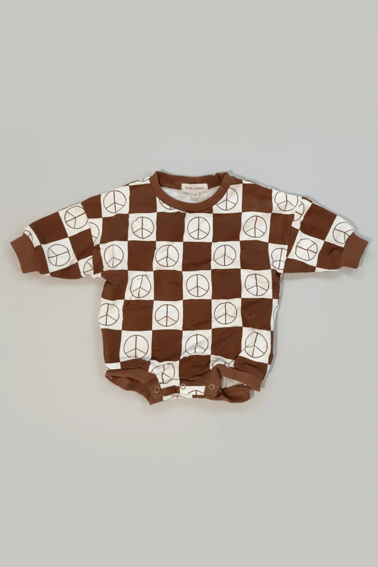 Baby romper with peace sign pattern on a gray background