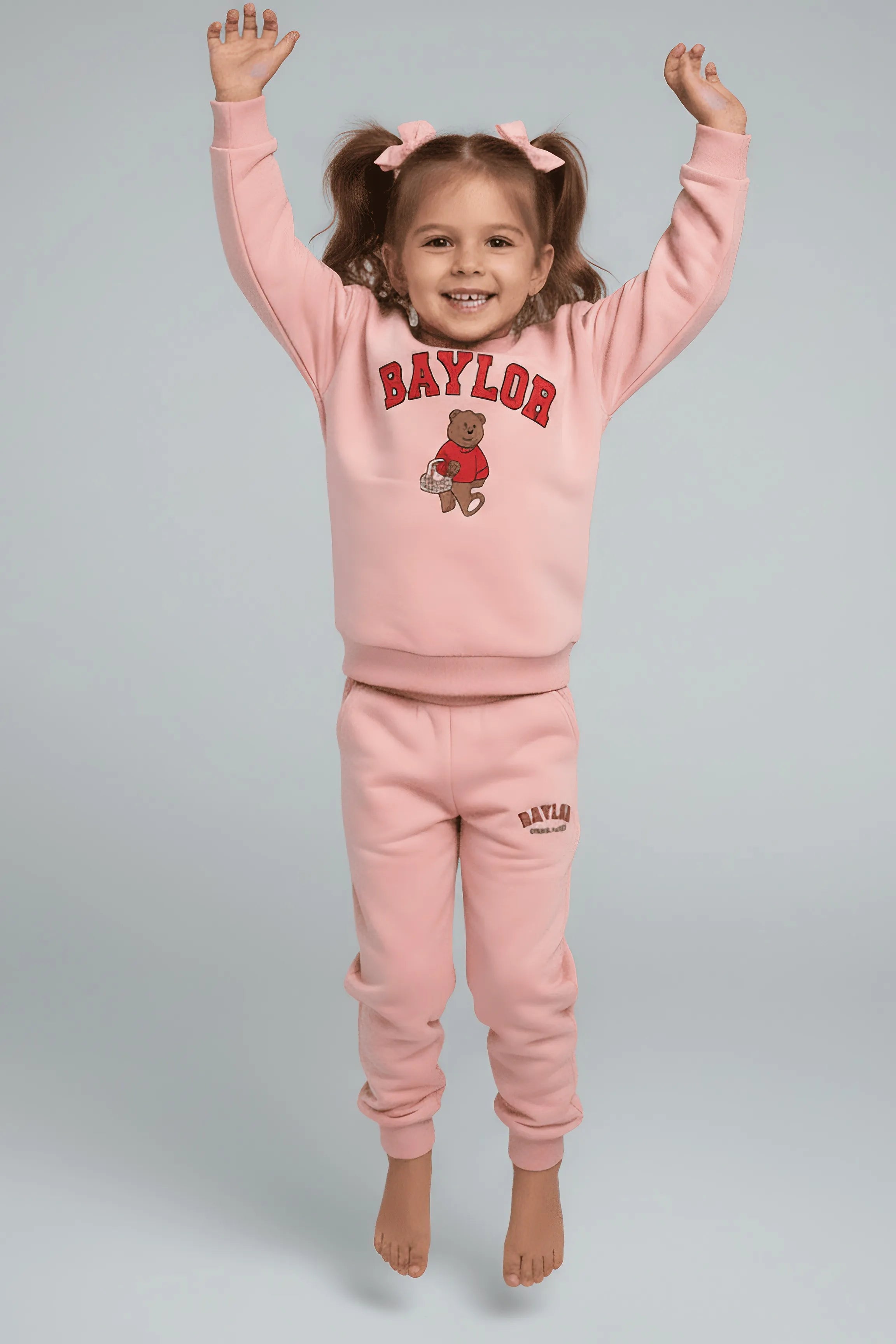 Child wearing a pink 'Baylor' Bubba's and Mama's sweatshirt and pants on a gray background