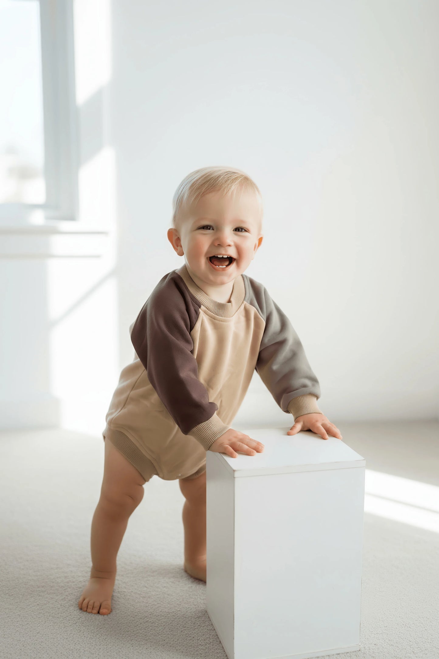 Child standing holding a white block in a bright room