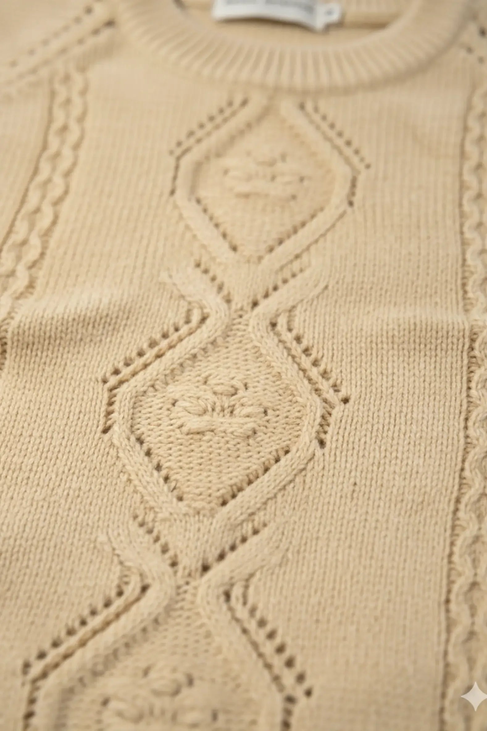 Close-up of a beige Bubba's and Mama's sweater with intricate cable knit pattern