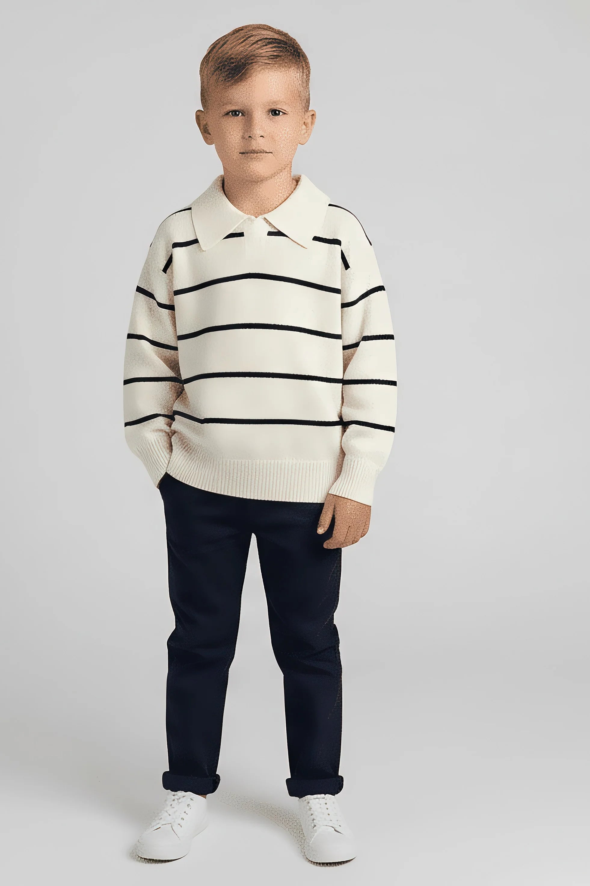 Young boy wearing a striped Bubba's and Mama's sweater and dark pants on a white background