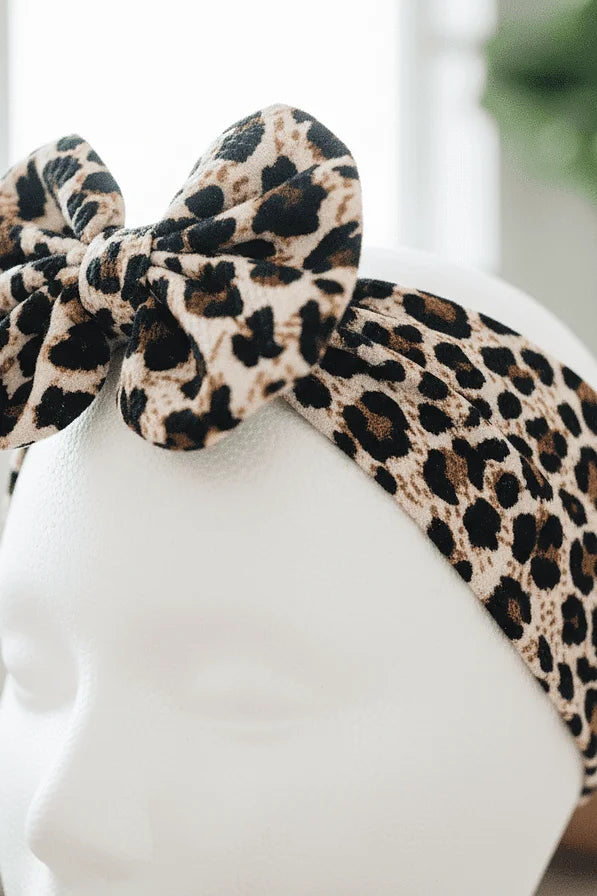 Leopard print headband with a bow on a mannequin head.