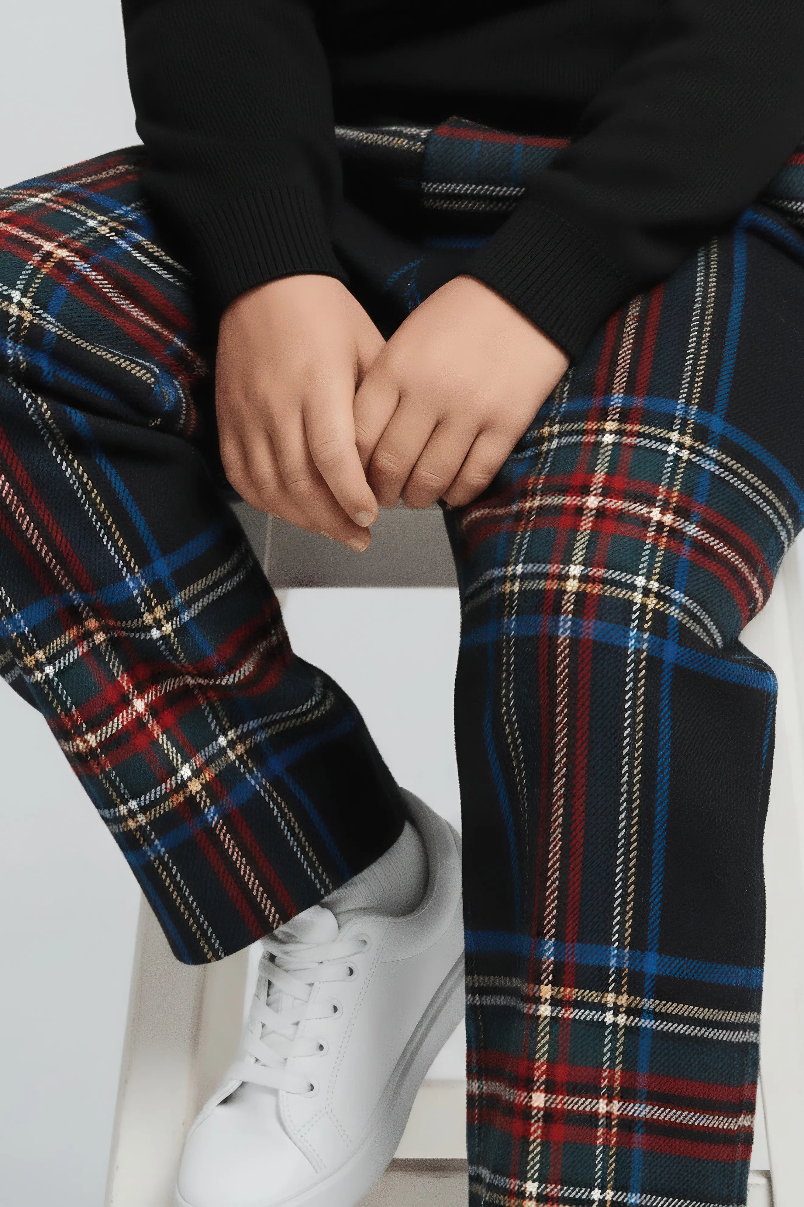 Person wearing plaid Bubba's and Mama's pants and white sneakers on a light background