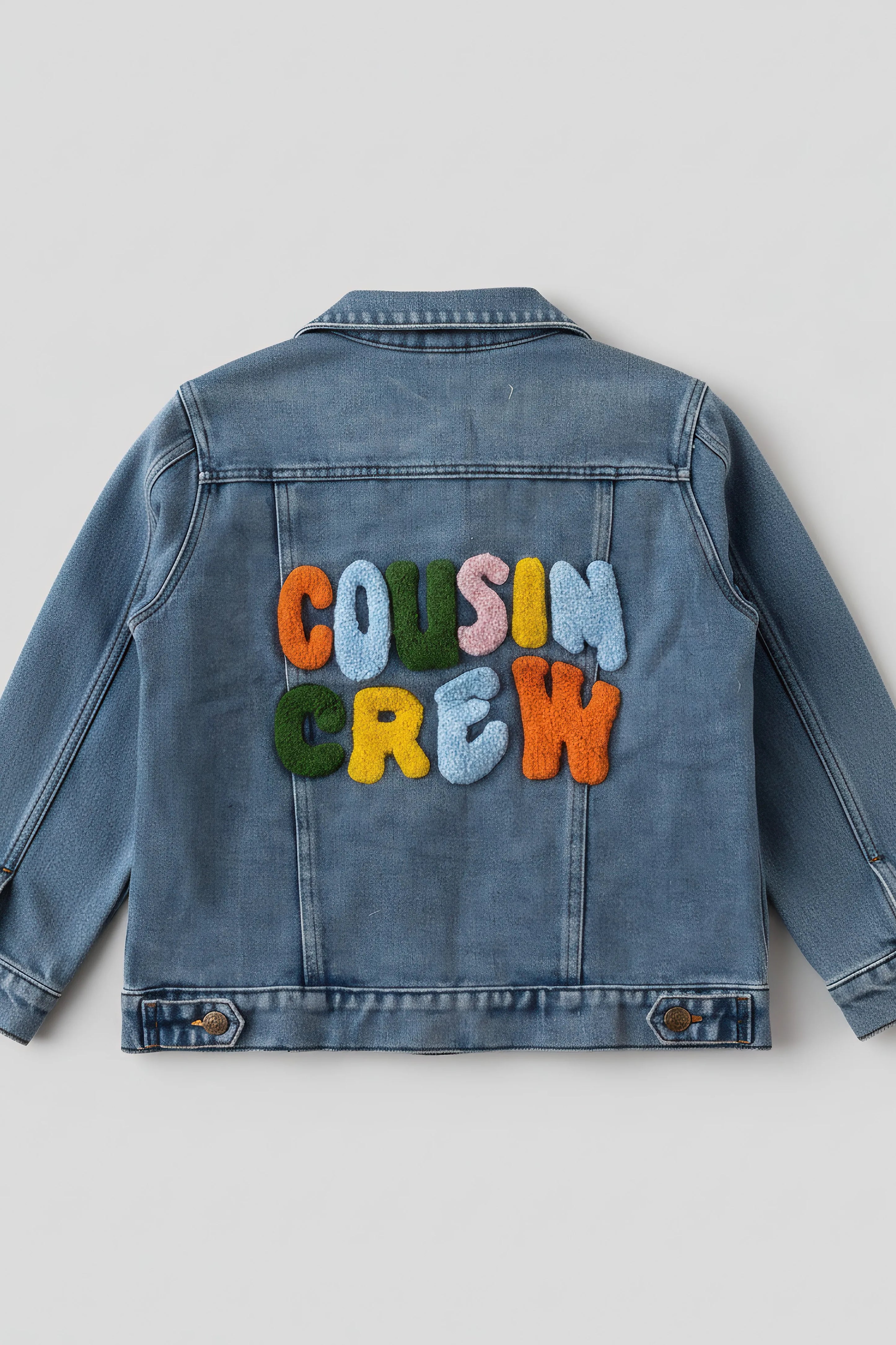 Blue denim jacket with 'COUSIN CREW' text in colorful letters on a light gray background
