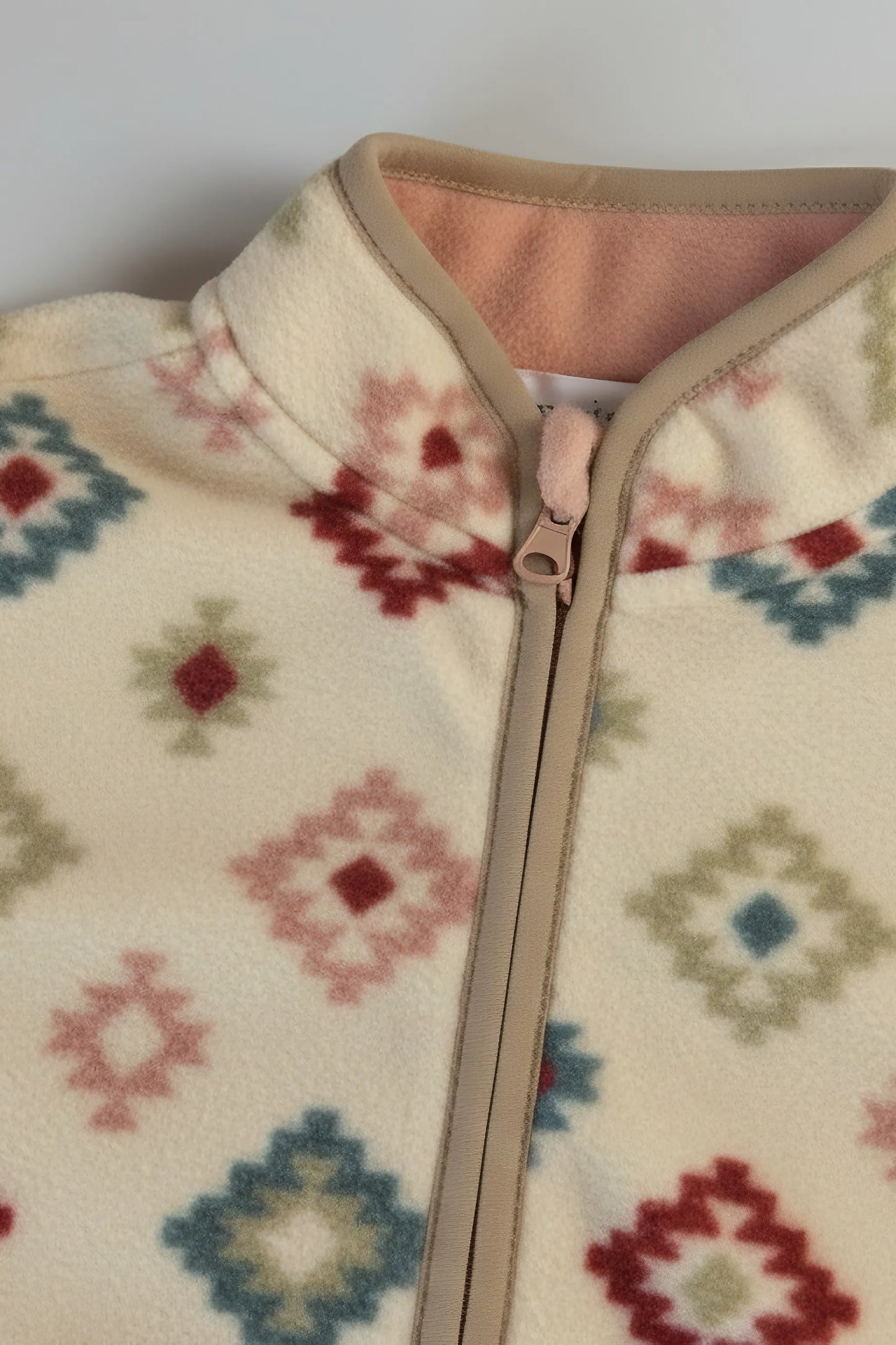 Close-up of a fleece Bubba's and Mama's jacket with a colorful geometric pattern and zipper.