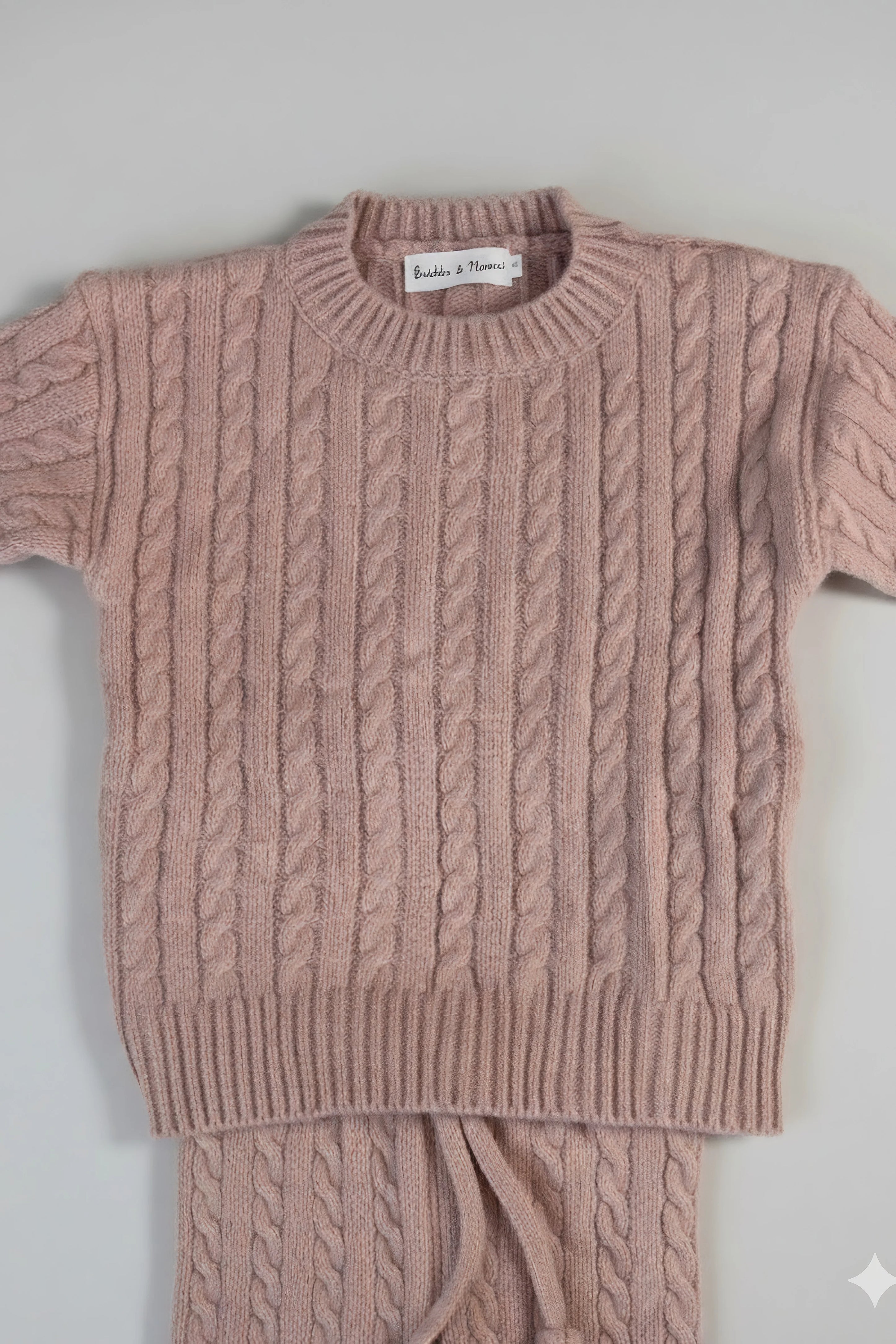 Pink cable knit Bubba's and Mama's sweater and pants set on a light gray background