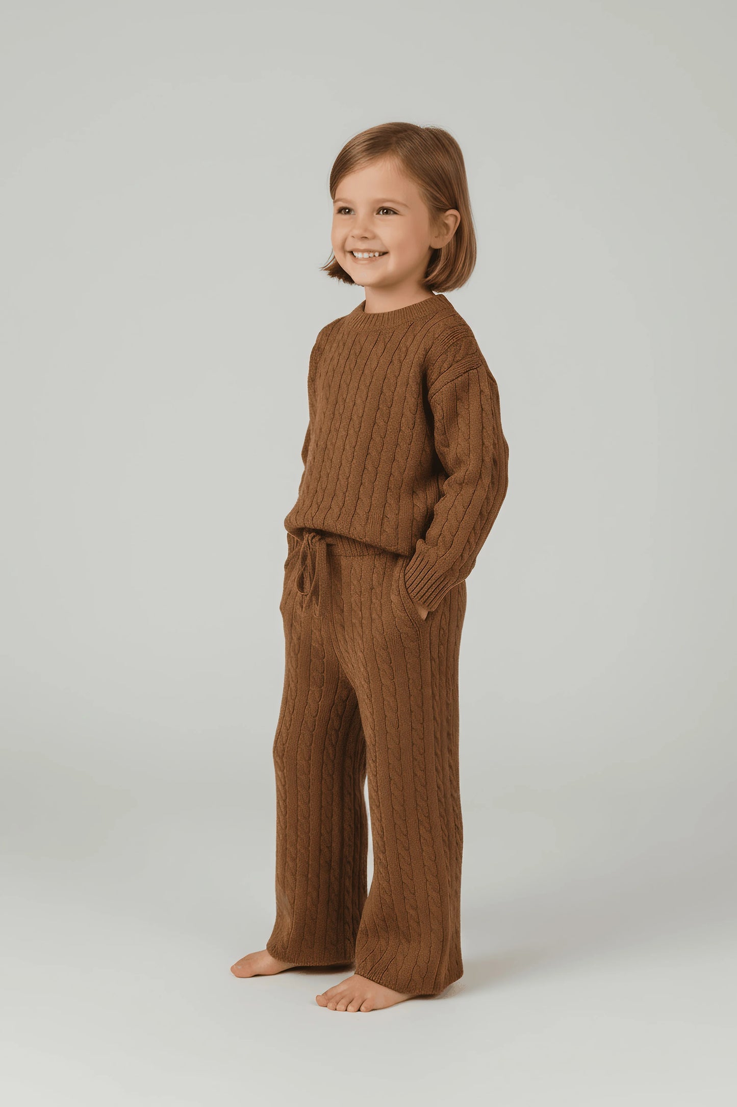 Child wearing a brown Bubba's and Mama's knitted outfit on a plain background