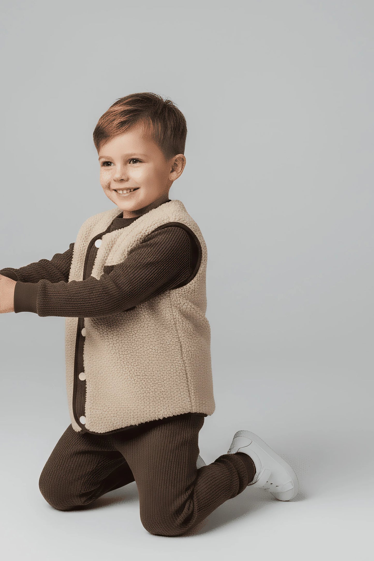 Child wearing a brown Bubba's and Mama's jacket and beige vest on a light gray background