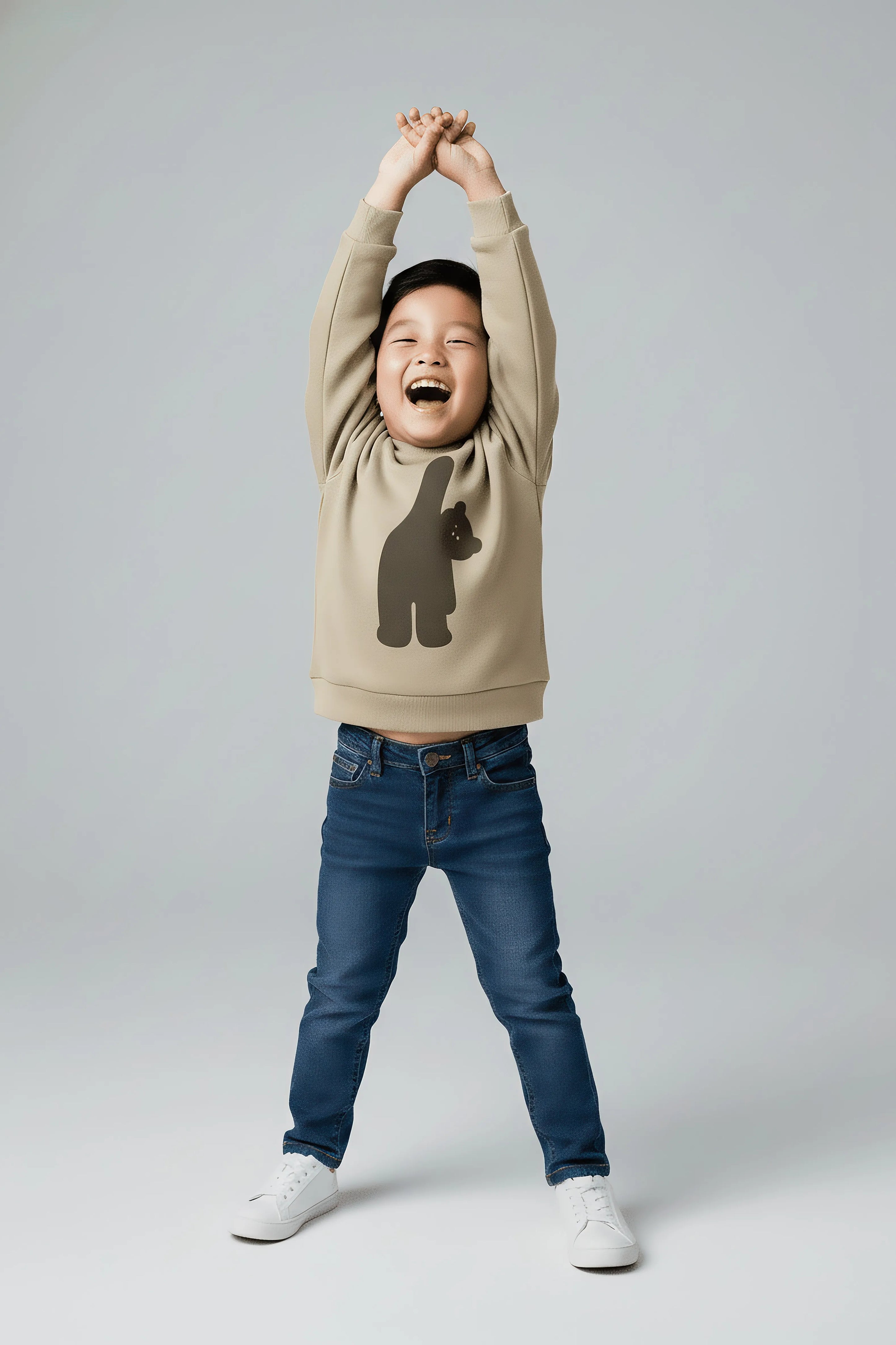 Child wearing a beige Bubba's and Mama's sweatshirt with a bear design and blue jeans, standing against a plain background
