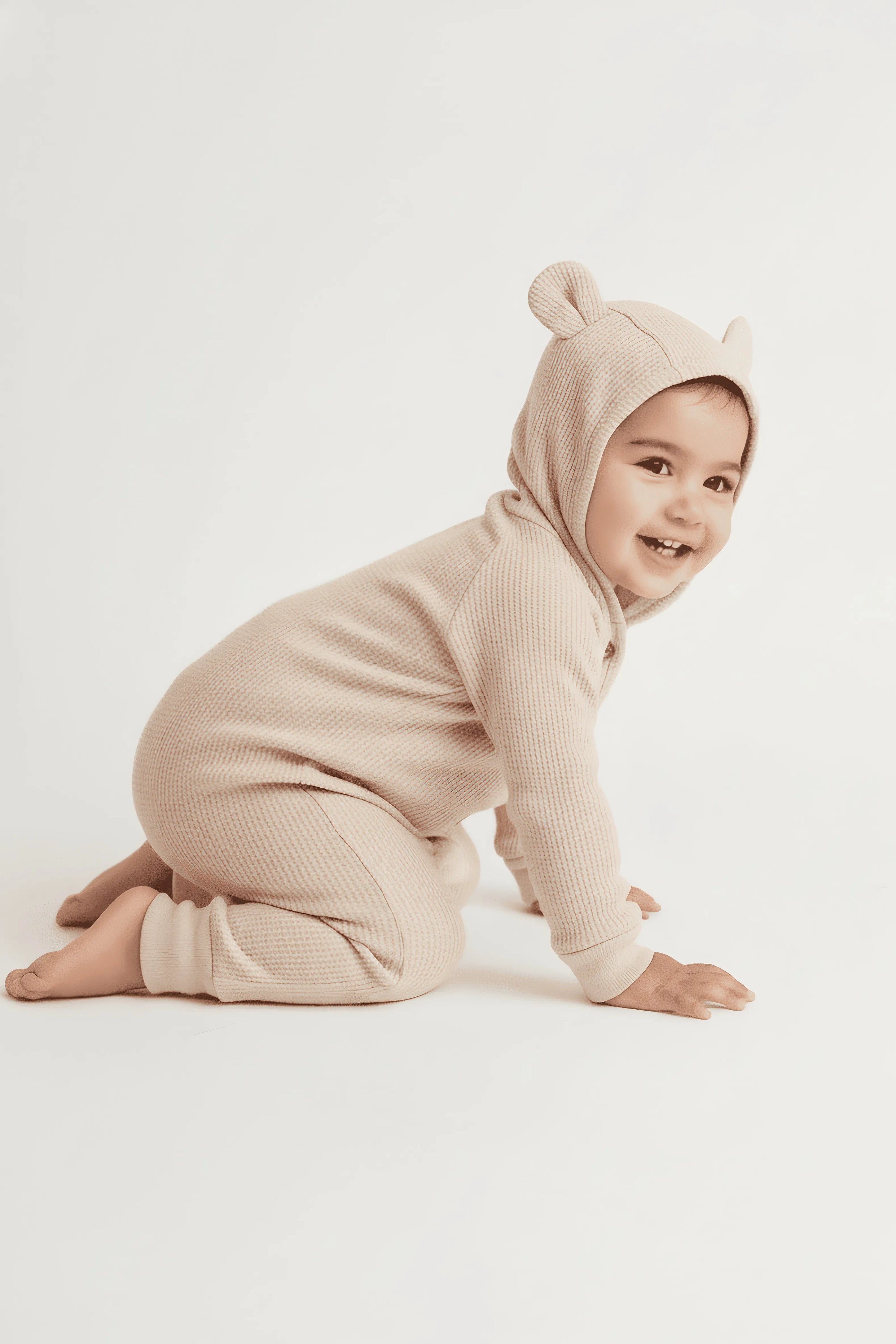 Child wearing a beige bear Bubba's and Mama's onesie on a white background