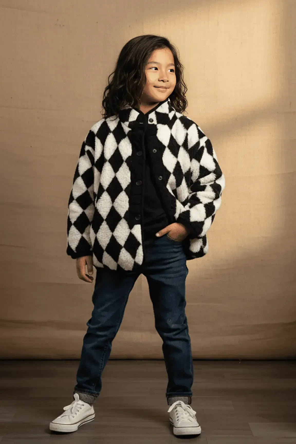 Child wearing a black and white checkered coat against a beige background