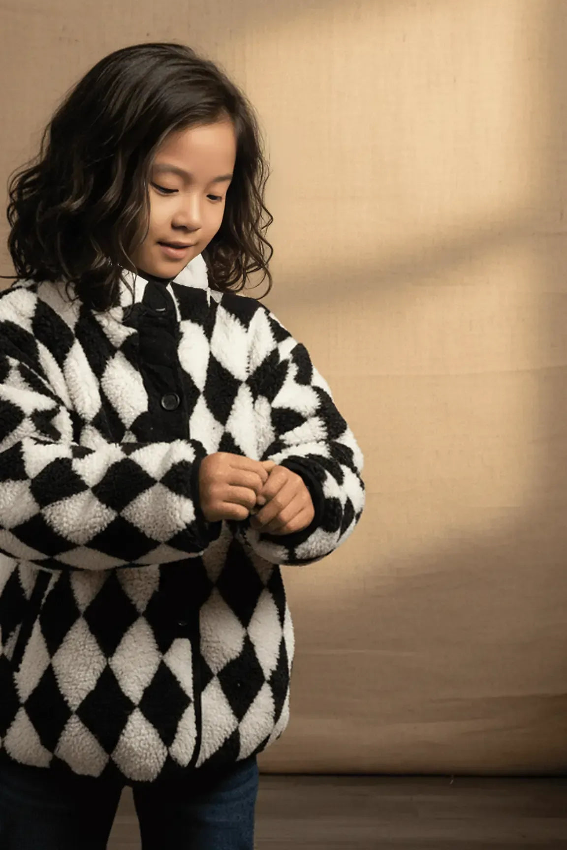 Child wearing a black and white checkered coat against a beige background