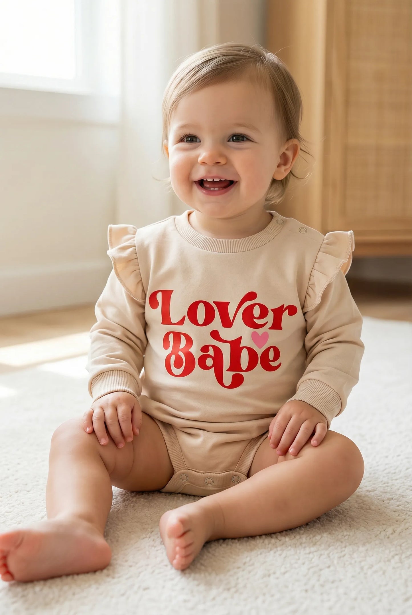 Baby wearing a 'Lover Babe' onesie sitting on a carpeted floor.