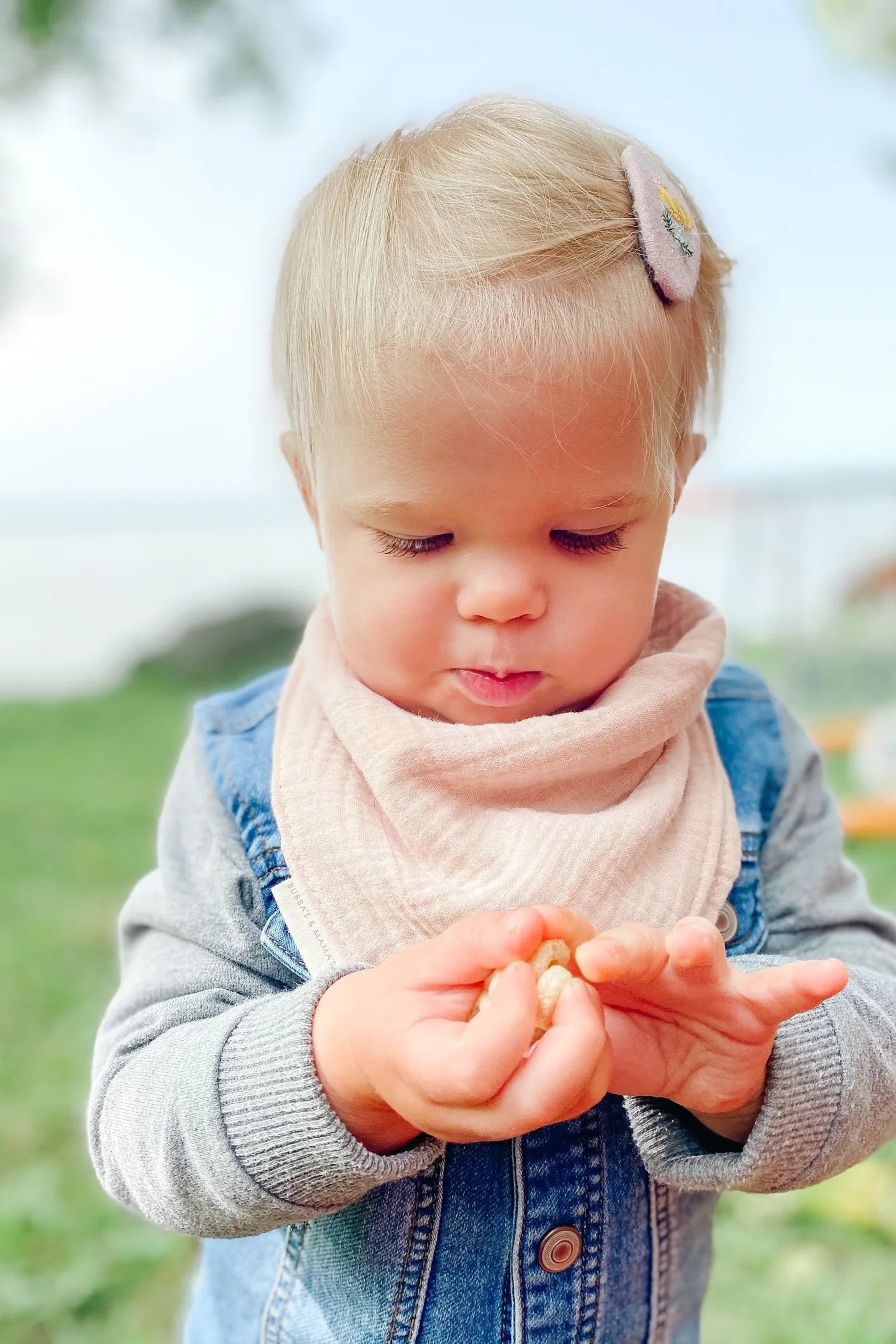 Child holding small objects outdoors with a blurred natural background