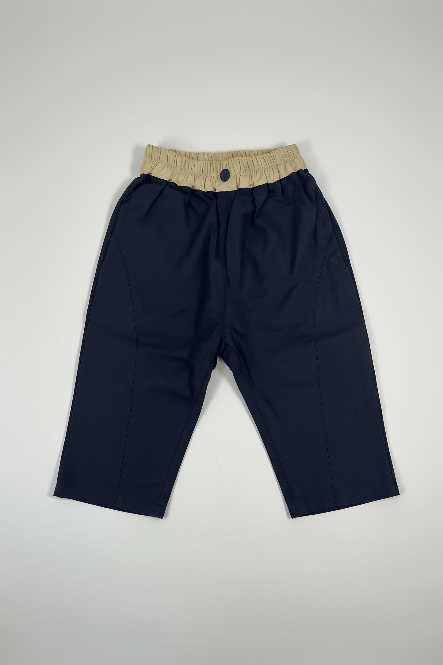Navy blue Bubba's and Mama's pants with beige waistband on a light gray background