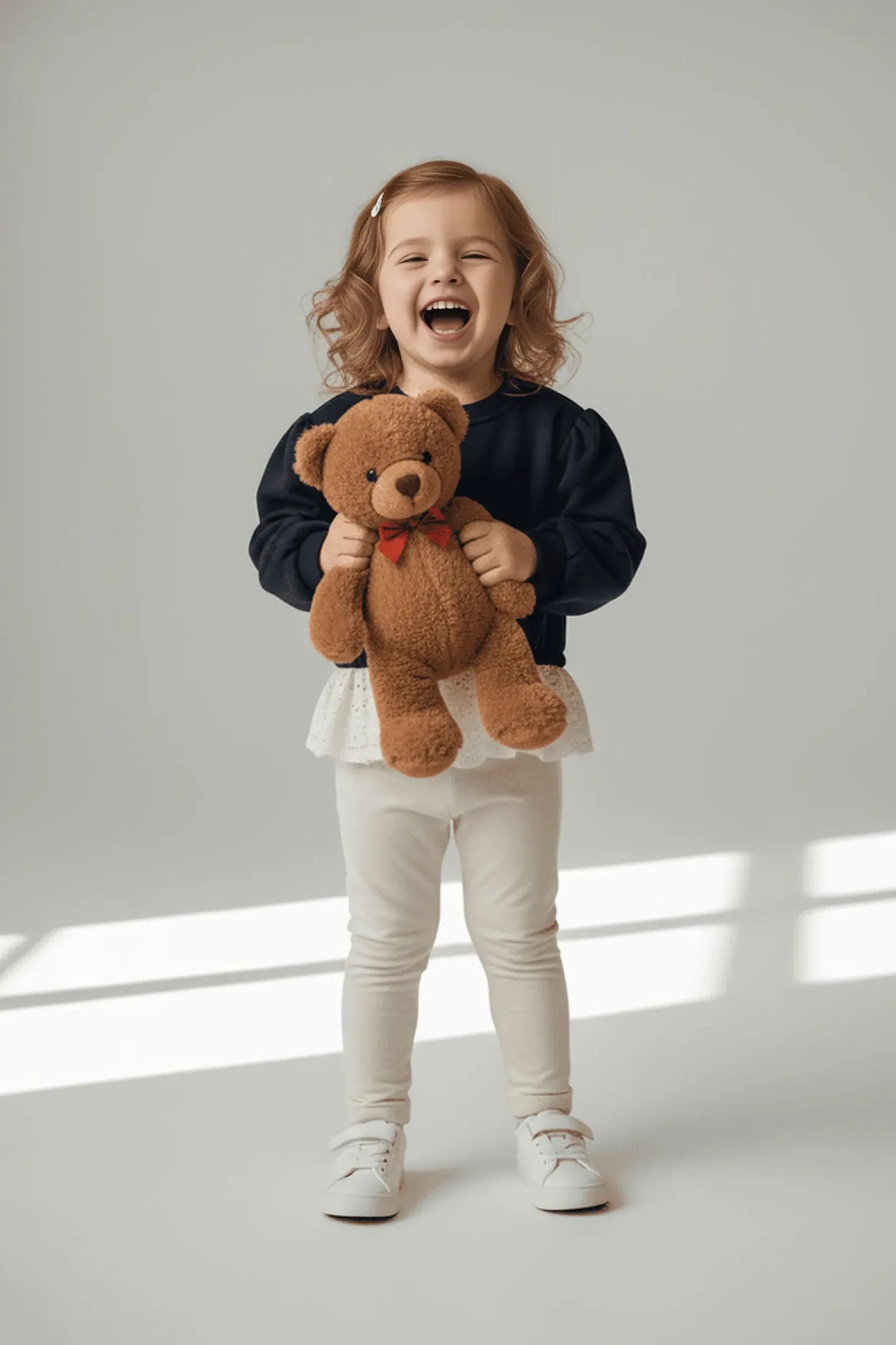 Child holding a teddy bear against a light background