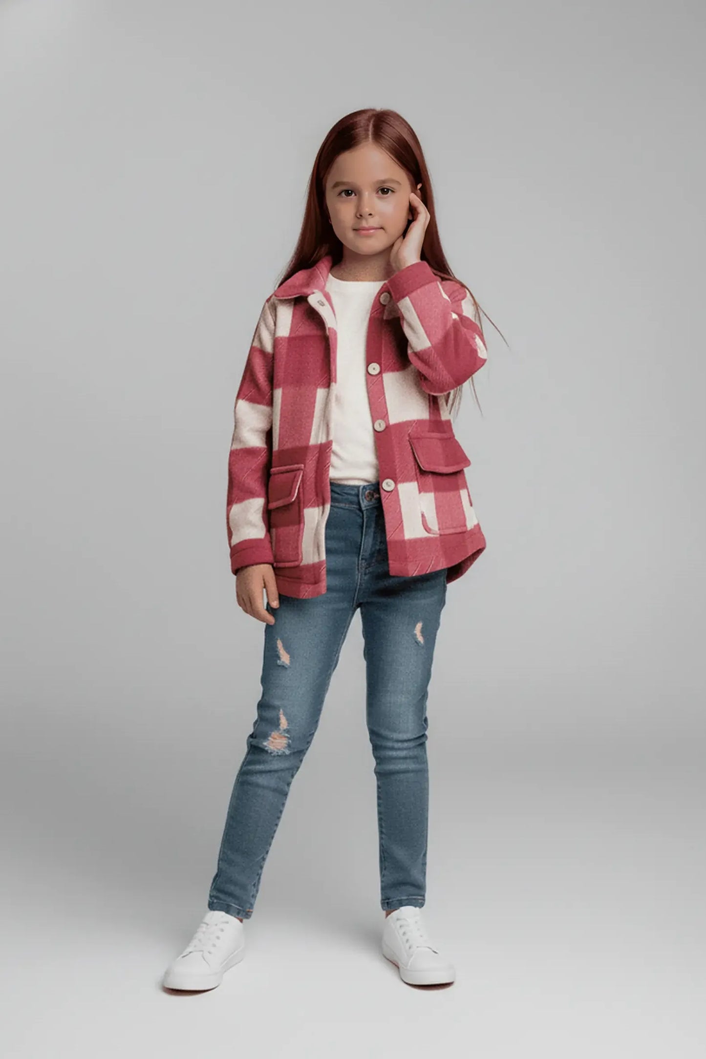 Young girl wearing a red and white plaid  Bubba's and Mama's jacket with blue jeans on a gray background