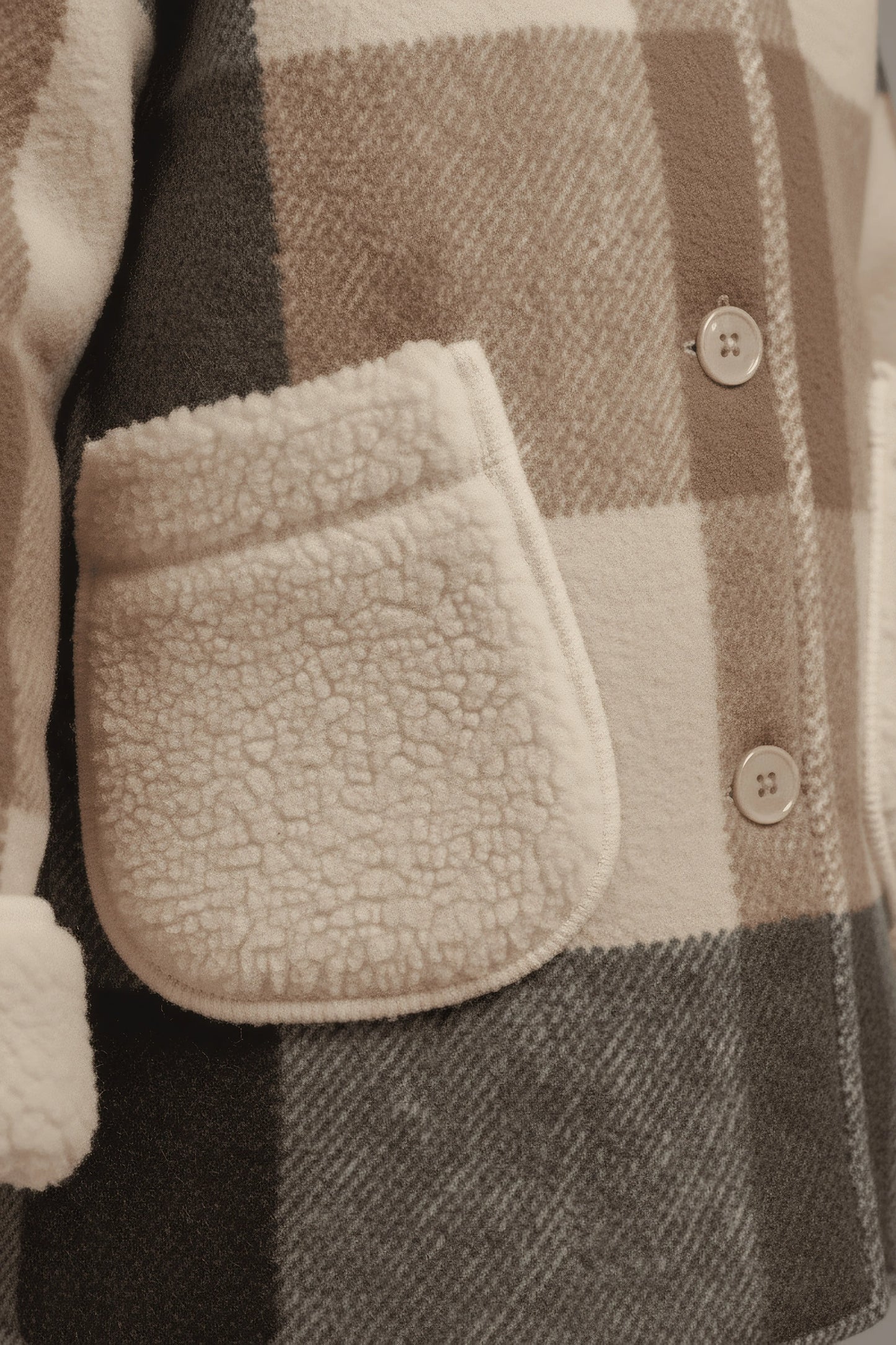 Close-up of a plaid Bubba's and Mama's jacket with a textured pocket and buttons.