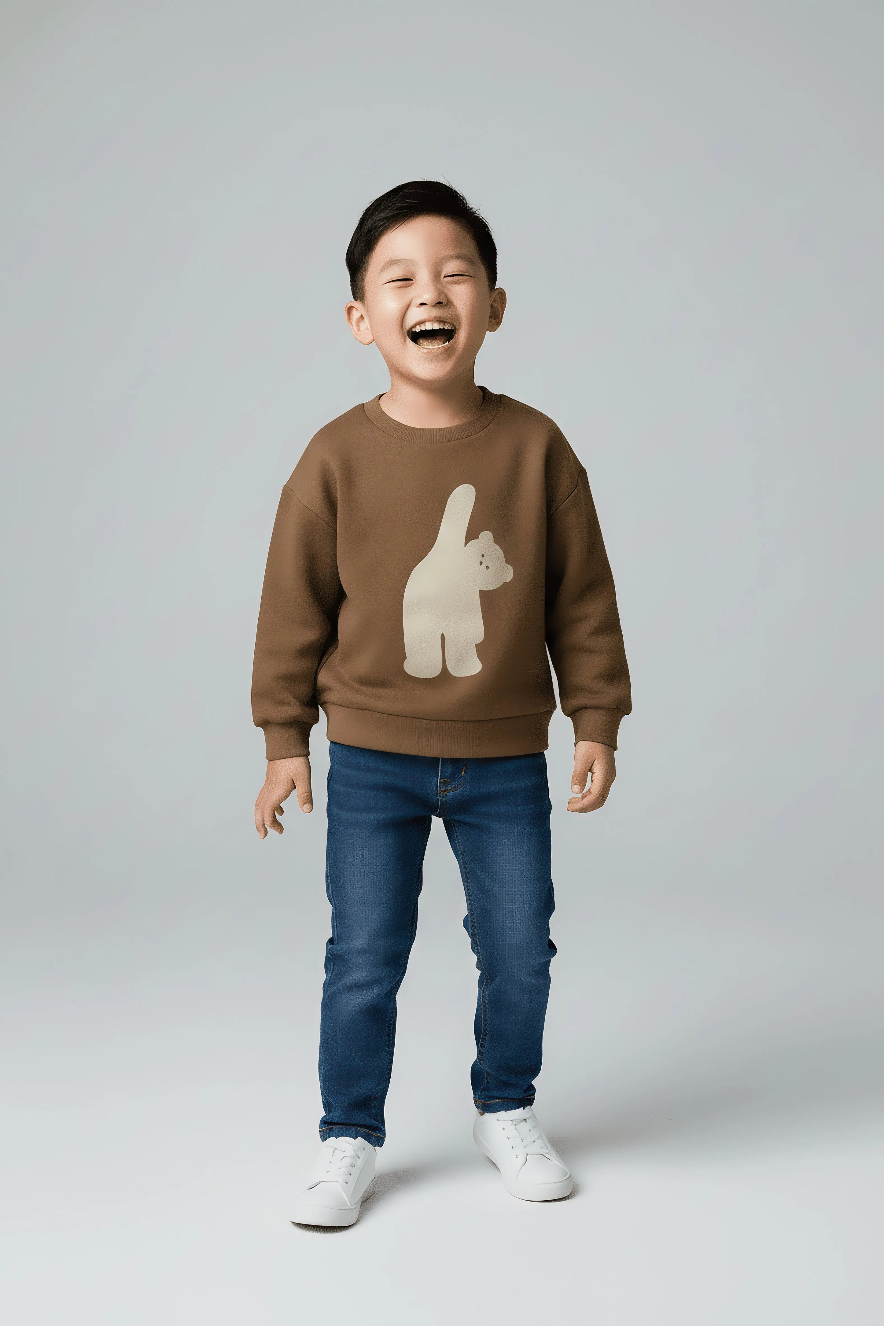 Child wearing a brown Bubba's and Mama's sweater with a bear design and blue jeans on a gray background