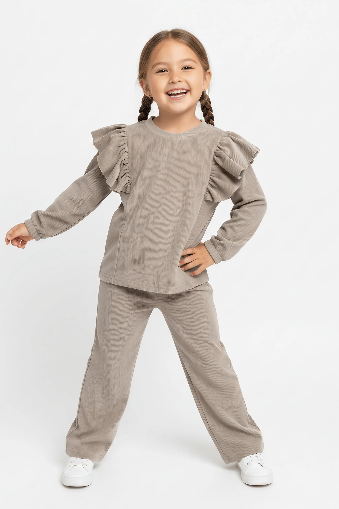 Young girl wearing a grey Bubba's and Mama's outfit with ruffled sleeves on a white background