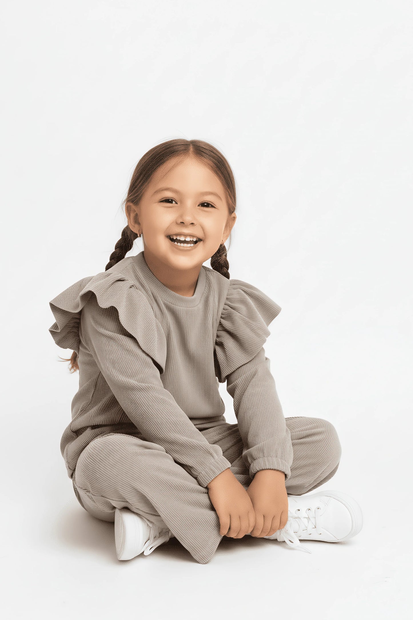 Child wearing a gray outfit with ruffled details on a white background