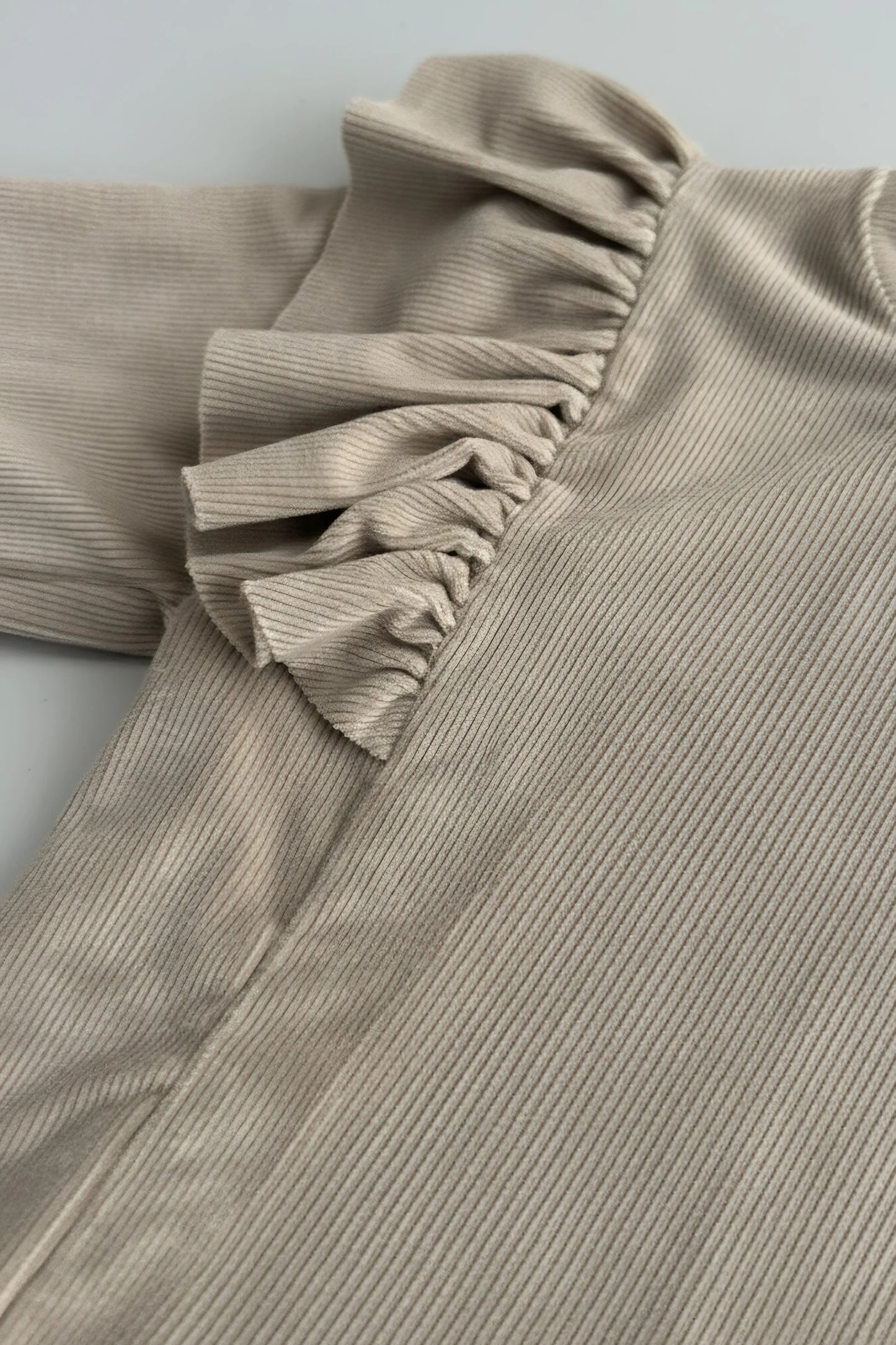 Close-up of a ribbed  Bubba's and Mama's top with ruffled collar on a light gray background