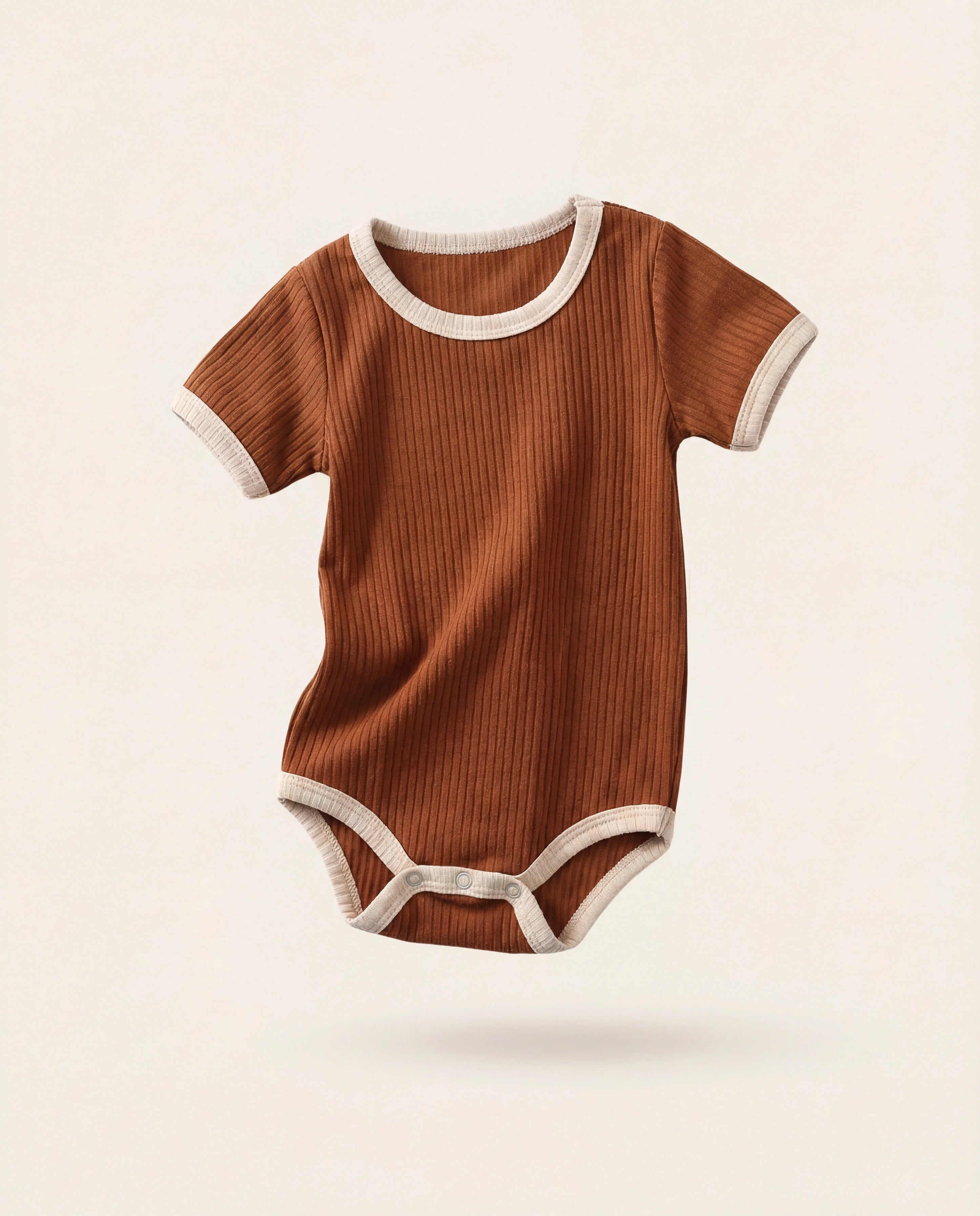 Brown baby onesie with white trim on a beige background