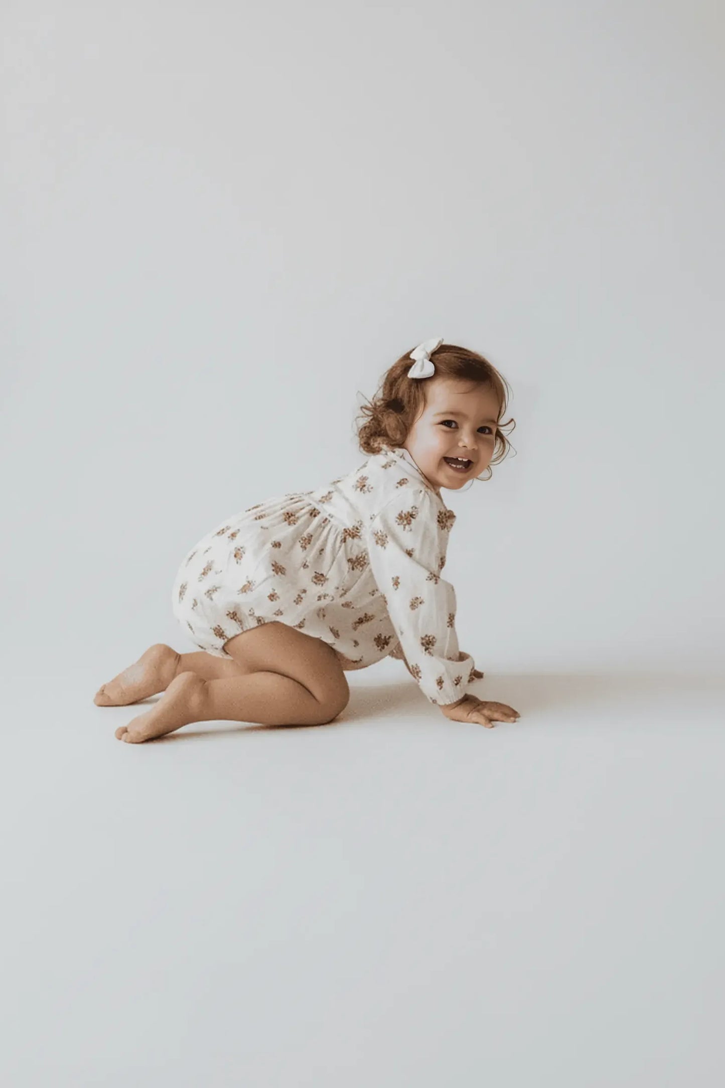 Child wearing a floral Bubba's and Mama's outfit on a plain background