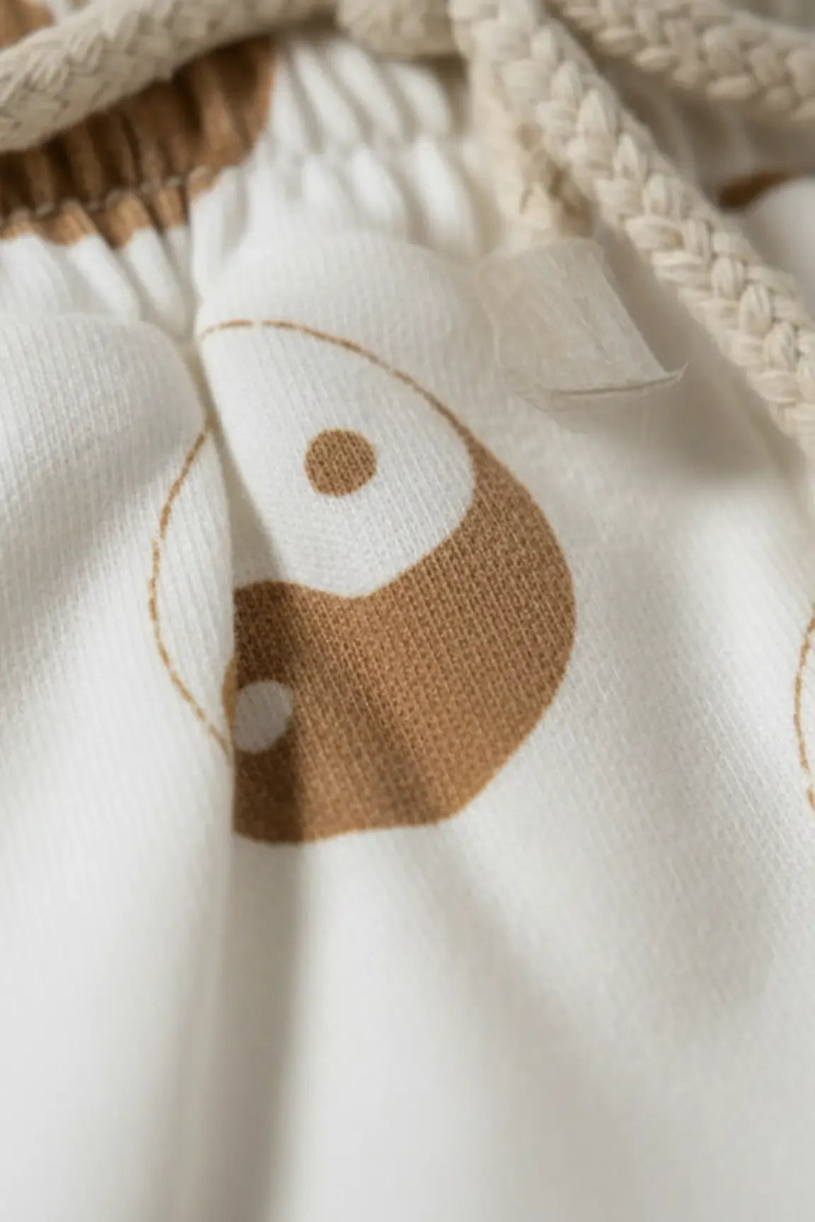 Close-up of a white fabric with a brown fish design on a beige background