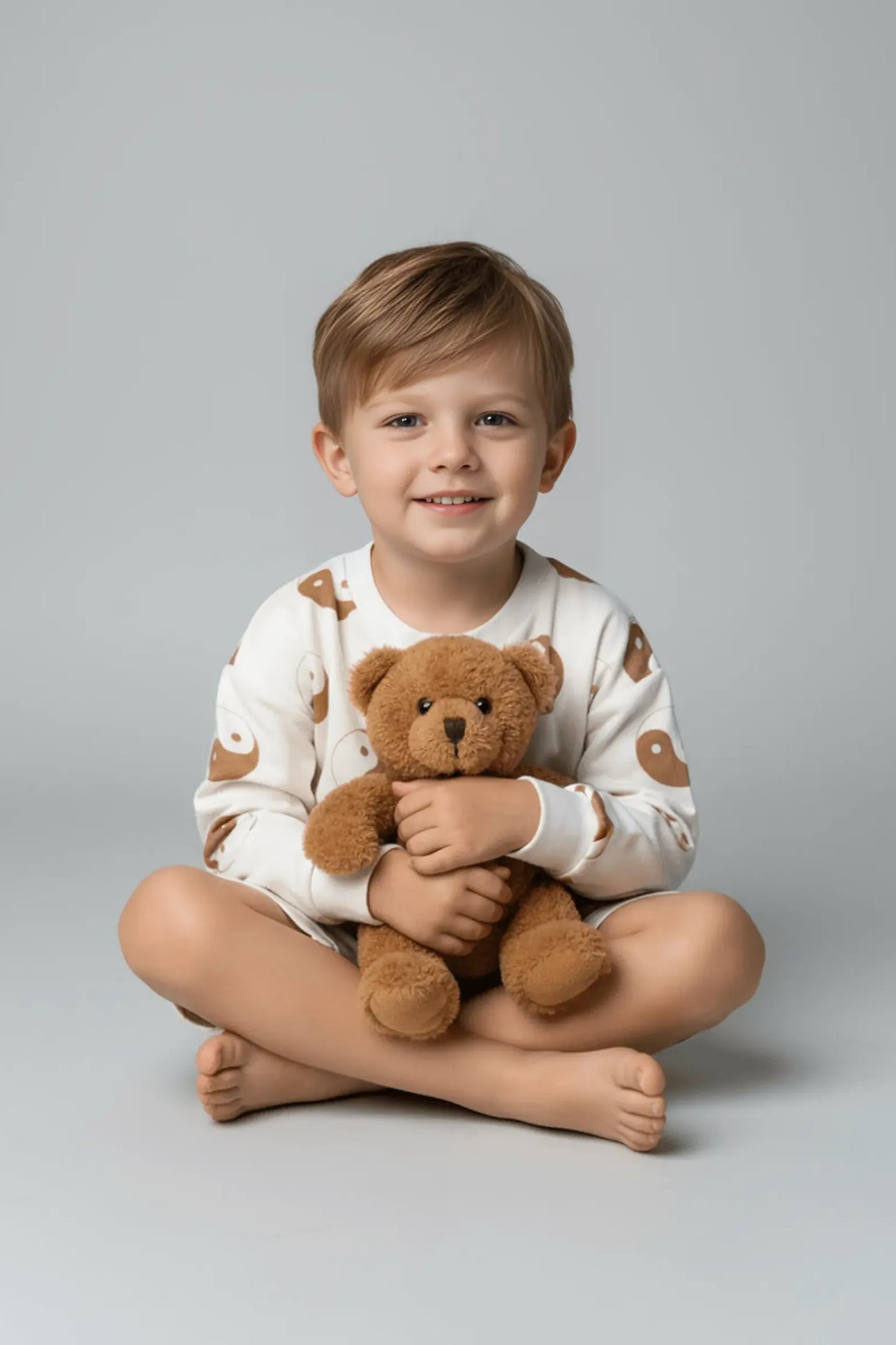 Child holding a teddy bear against a plain background